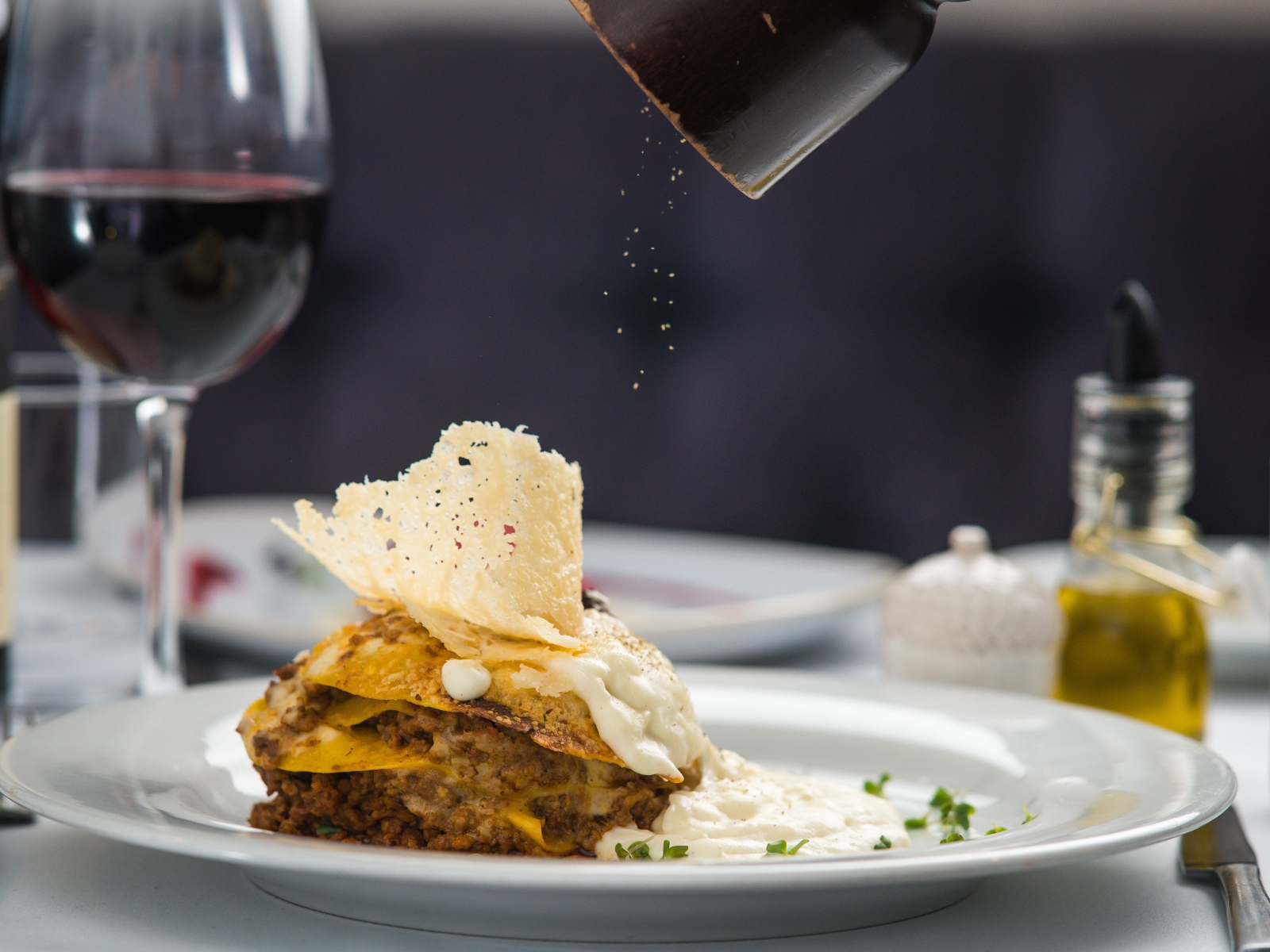 Кусок лазаньи посыпают перцем 