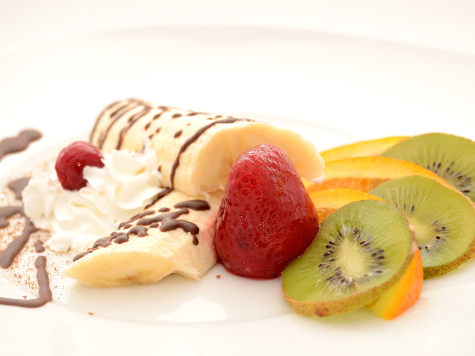 Бананы, киви и клубника на тарелке со сливками