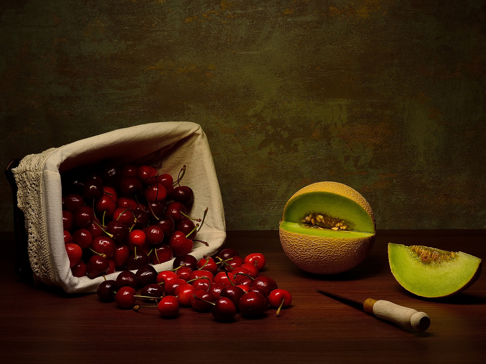 Корзина с черешнями на столе с дыней