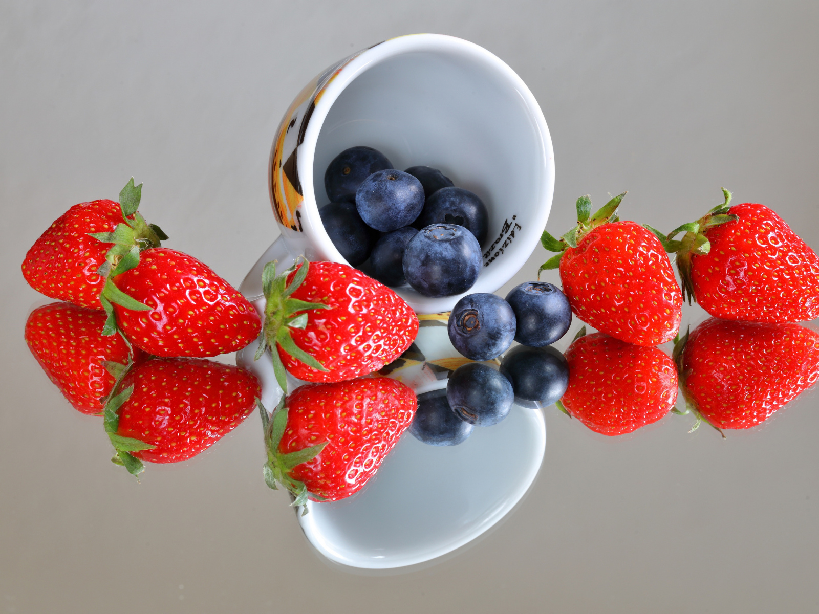 Чашка с ягодами черники и клубники на столе