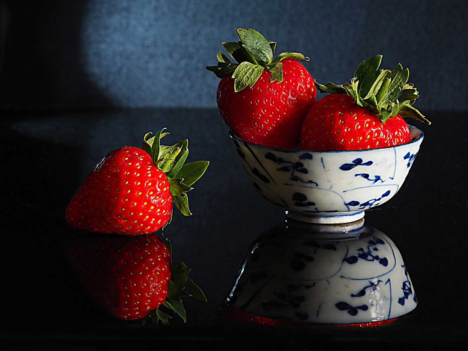 Три красные клубники в миске на столе