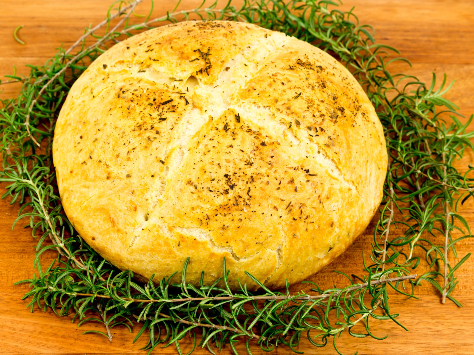 Буханка свежего ароматного хлеба с розмарином на столе