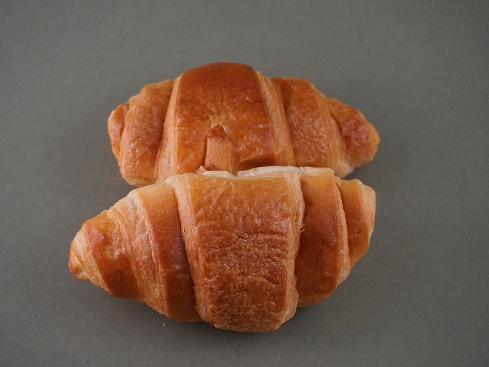 Два свежих круассана на серой поверхности