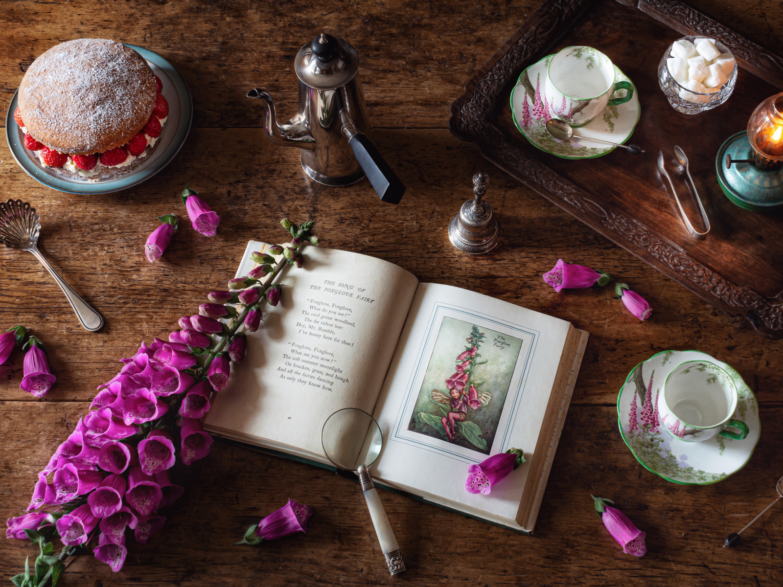 Пирожное на столе с чаем, книгой и цветами 