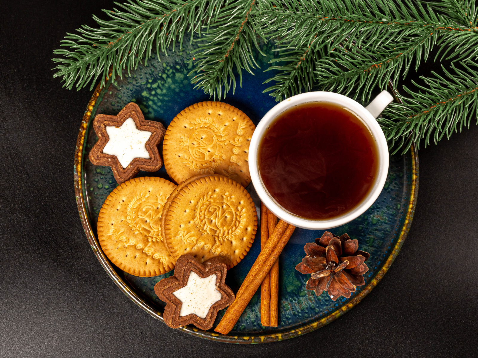 Печенье, чай и корица на столе с еловой веткой