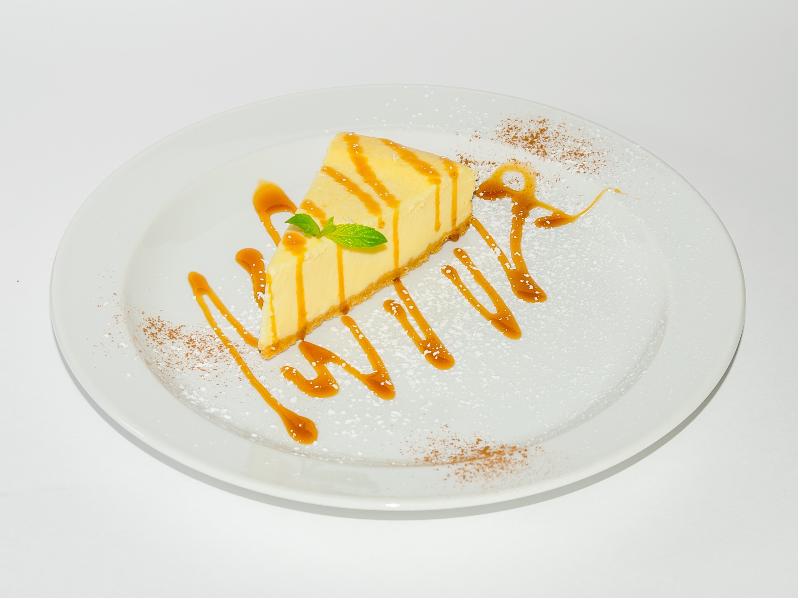 Кусок чизкейка с сиропом на большой белой тарелке 