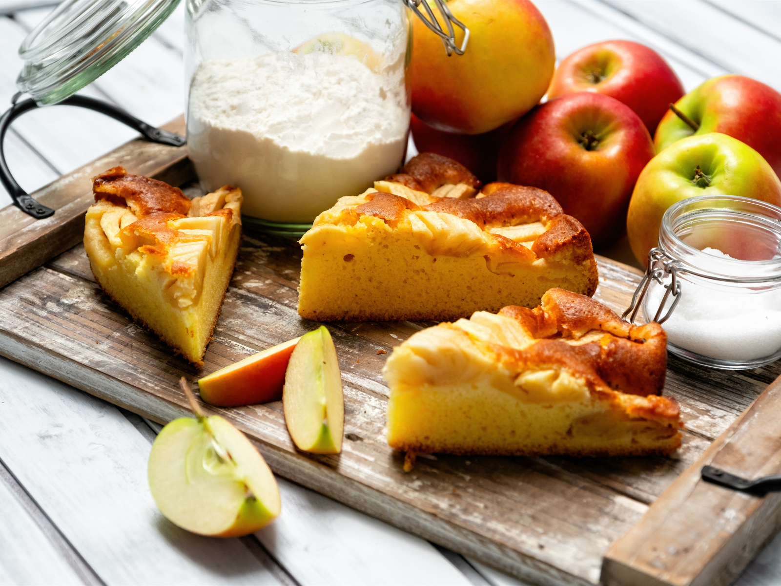 Куски пирога на столе с яблоками и мукой