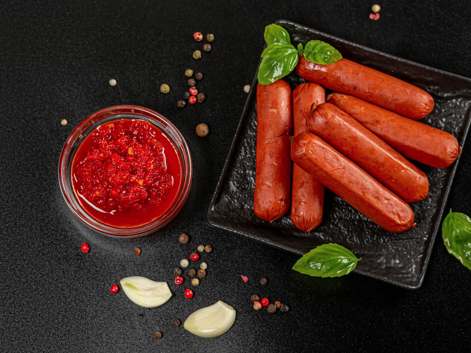 Sausages on a black table with sauce