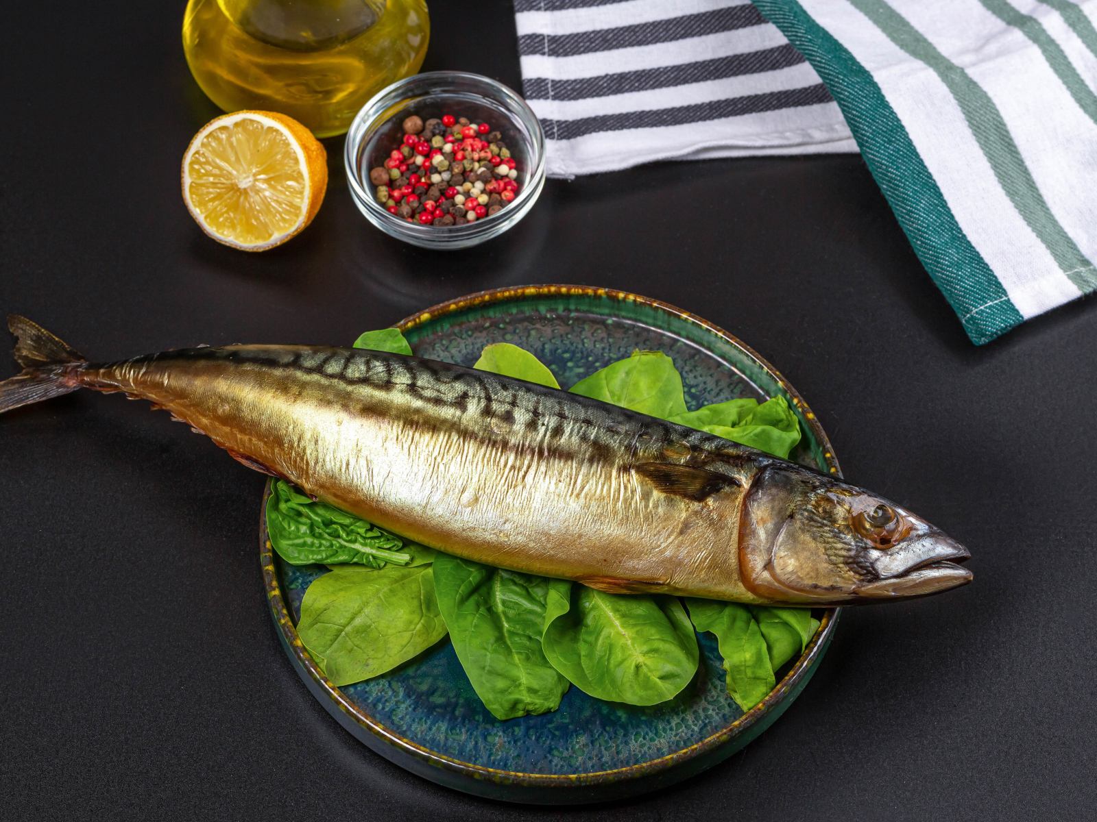 Большая копченая скумбрия на тарелке с базиликом