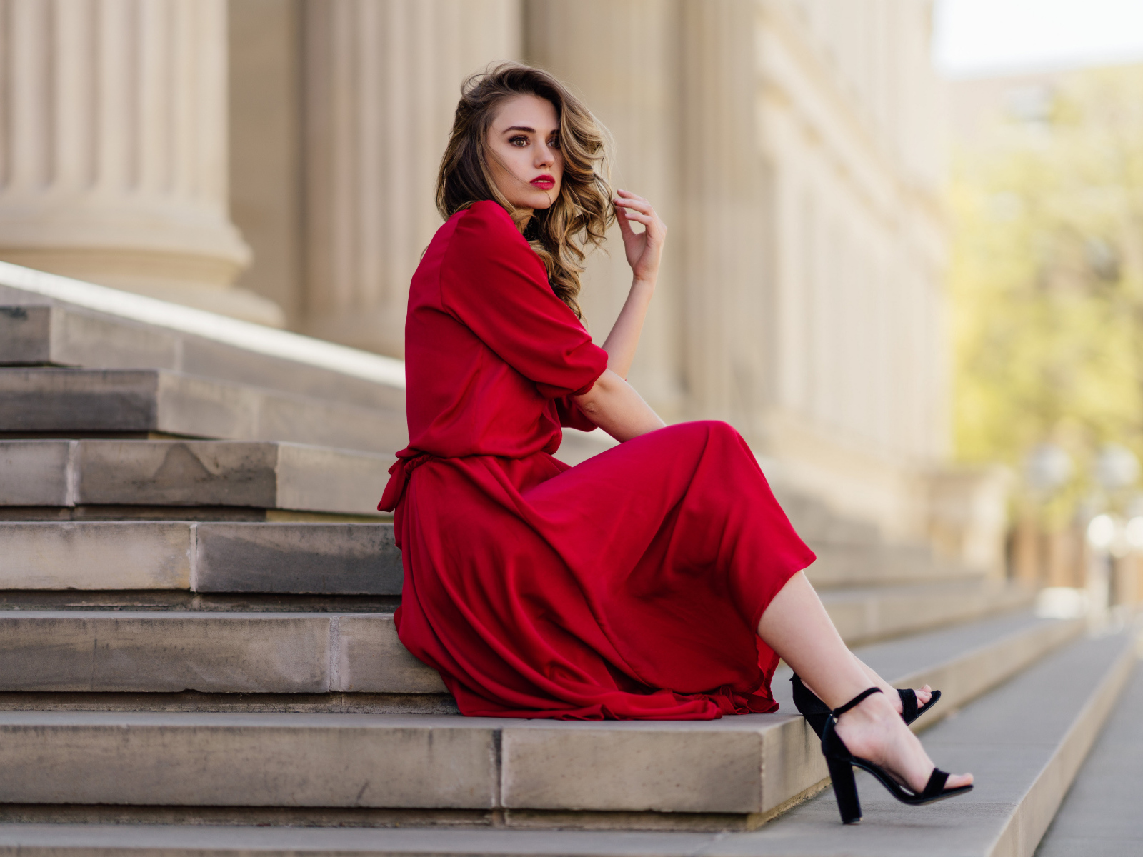 Девушка в красном платье сидит на ступеньках