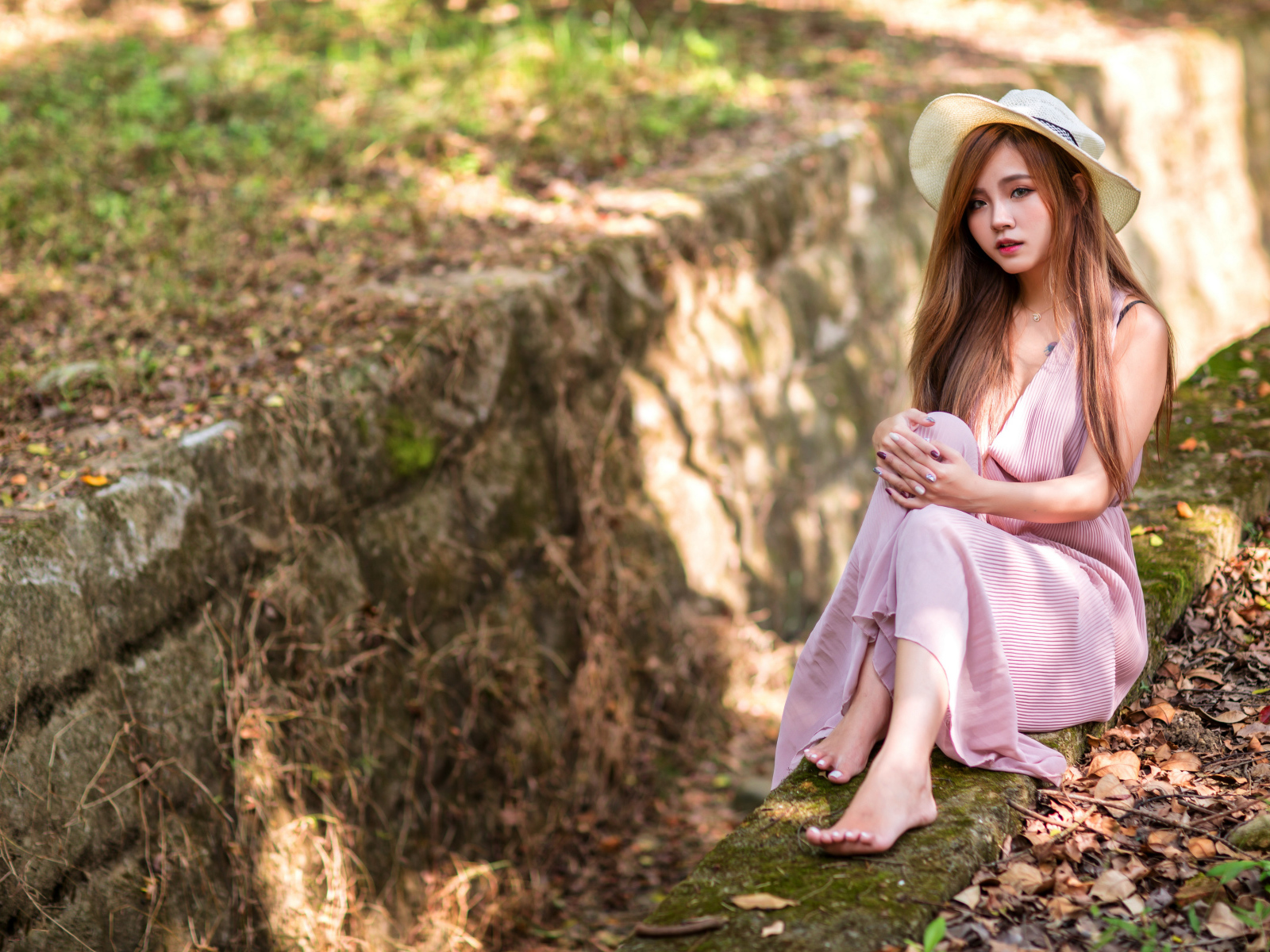 Девушка азиатка в розовом платье сидит на земле