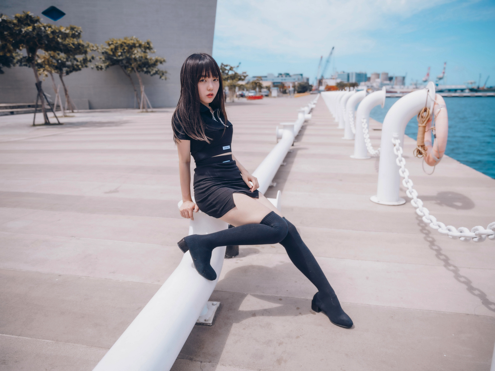 Девушка азиатка в черном костюме на пристани 