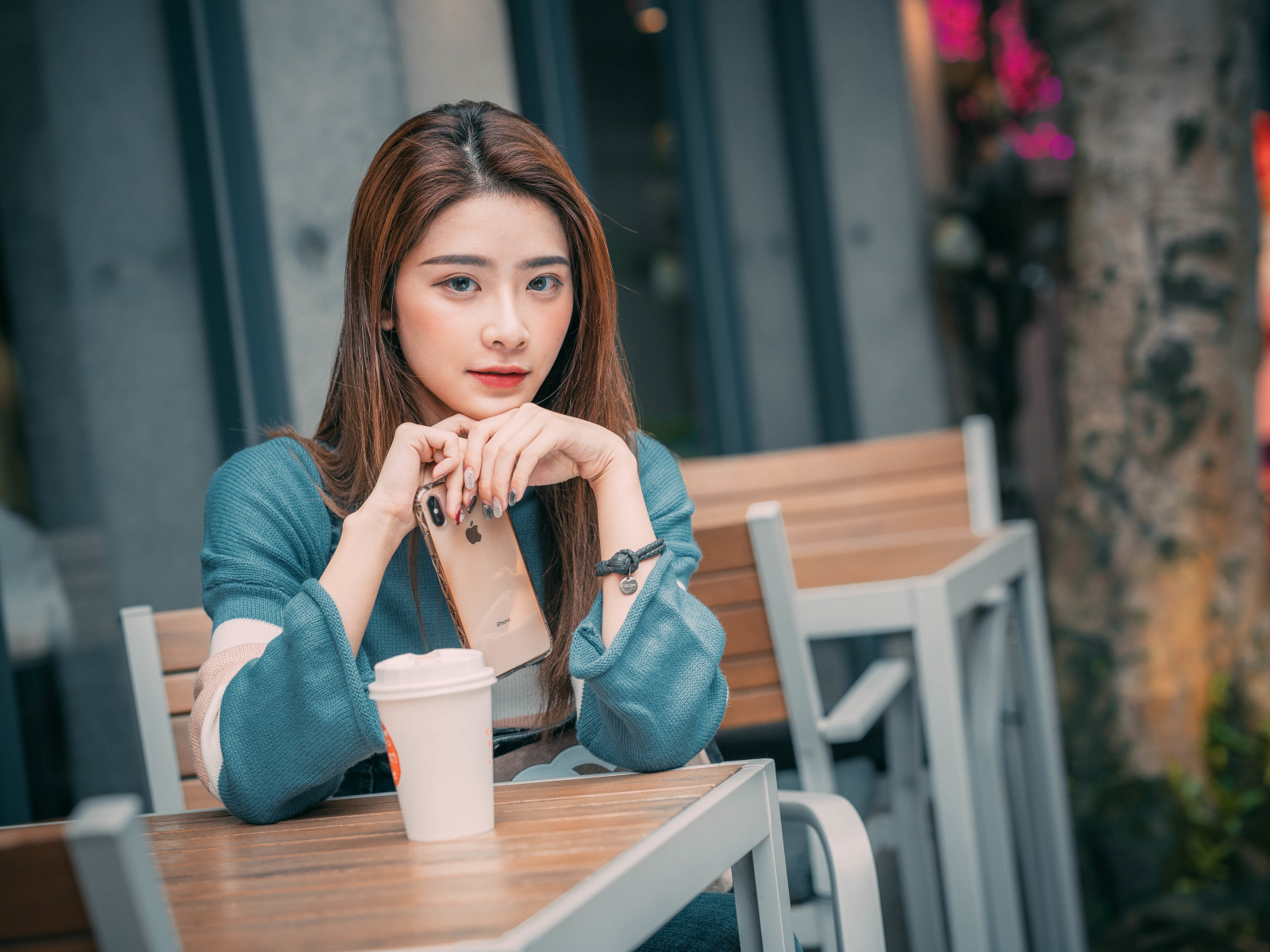 Девушка азиатка сидит за столом в кафе с телефоном 