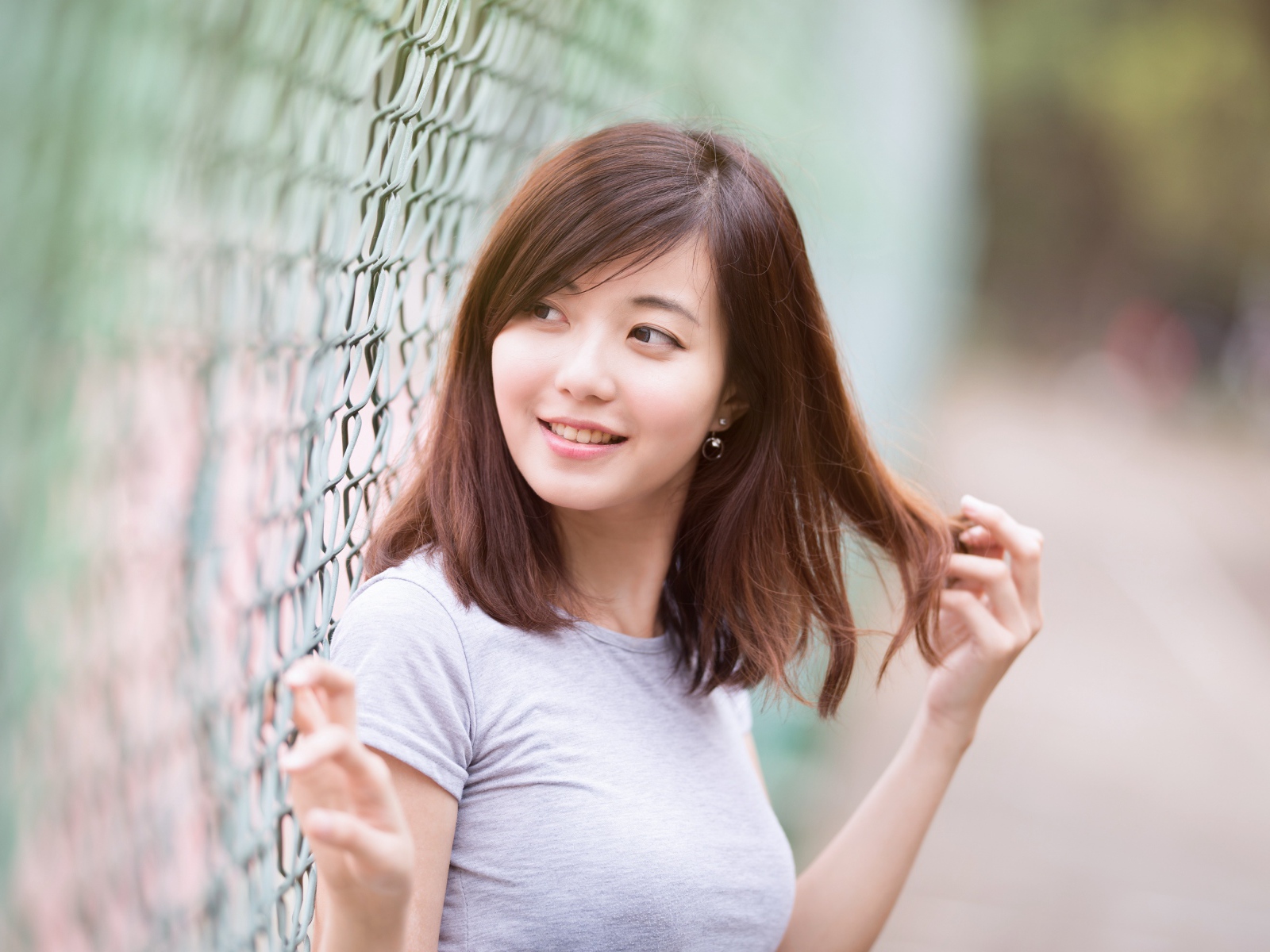 Девушка азиатка с милой улыбкой стоит у сетки 