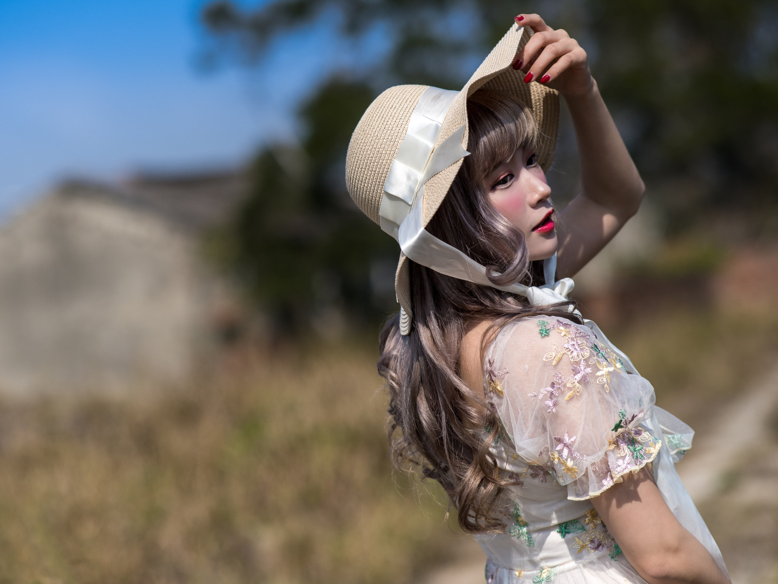 Красивая азиатка в шляпе в лучах солнца