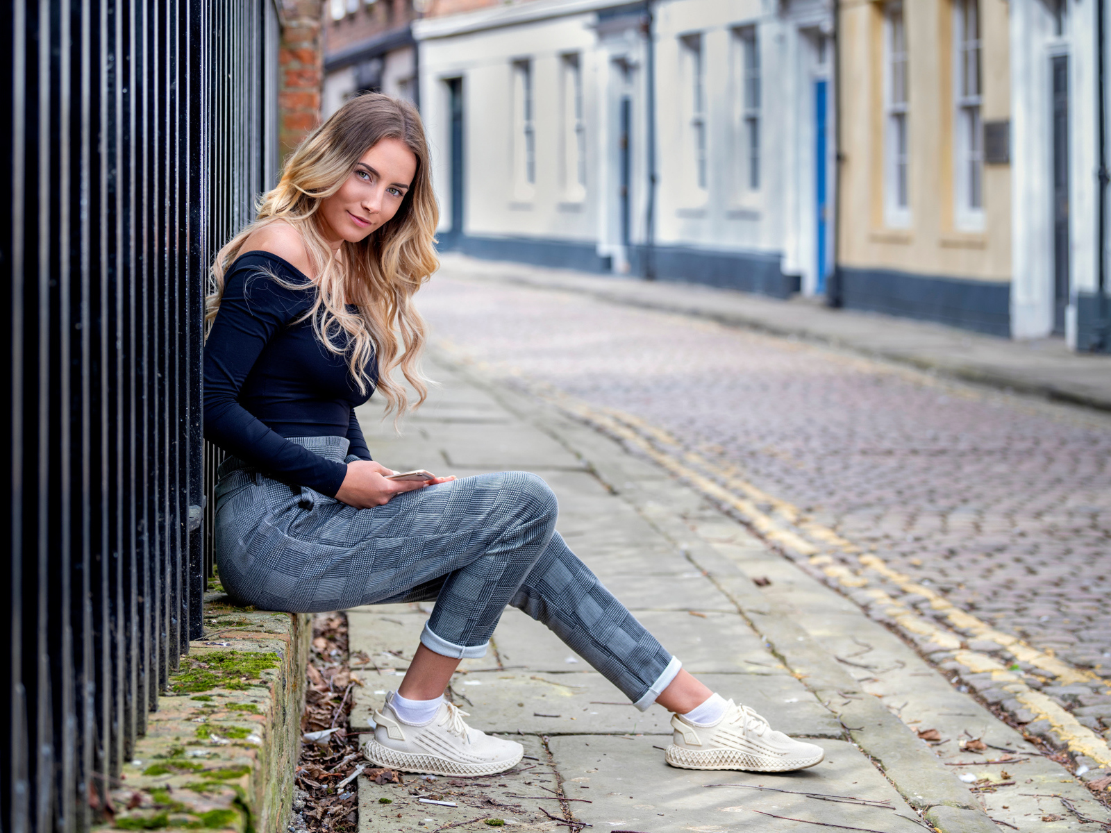 Красивая девушка блондинка сидит у забора