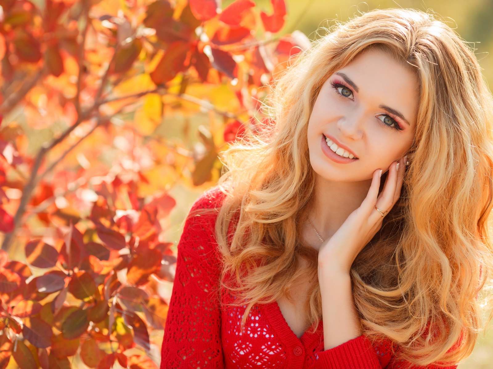 Красивая блондинка в красной кофте на улице осенью 