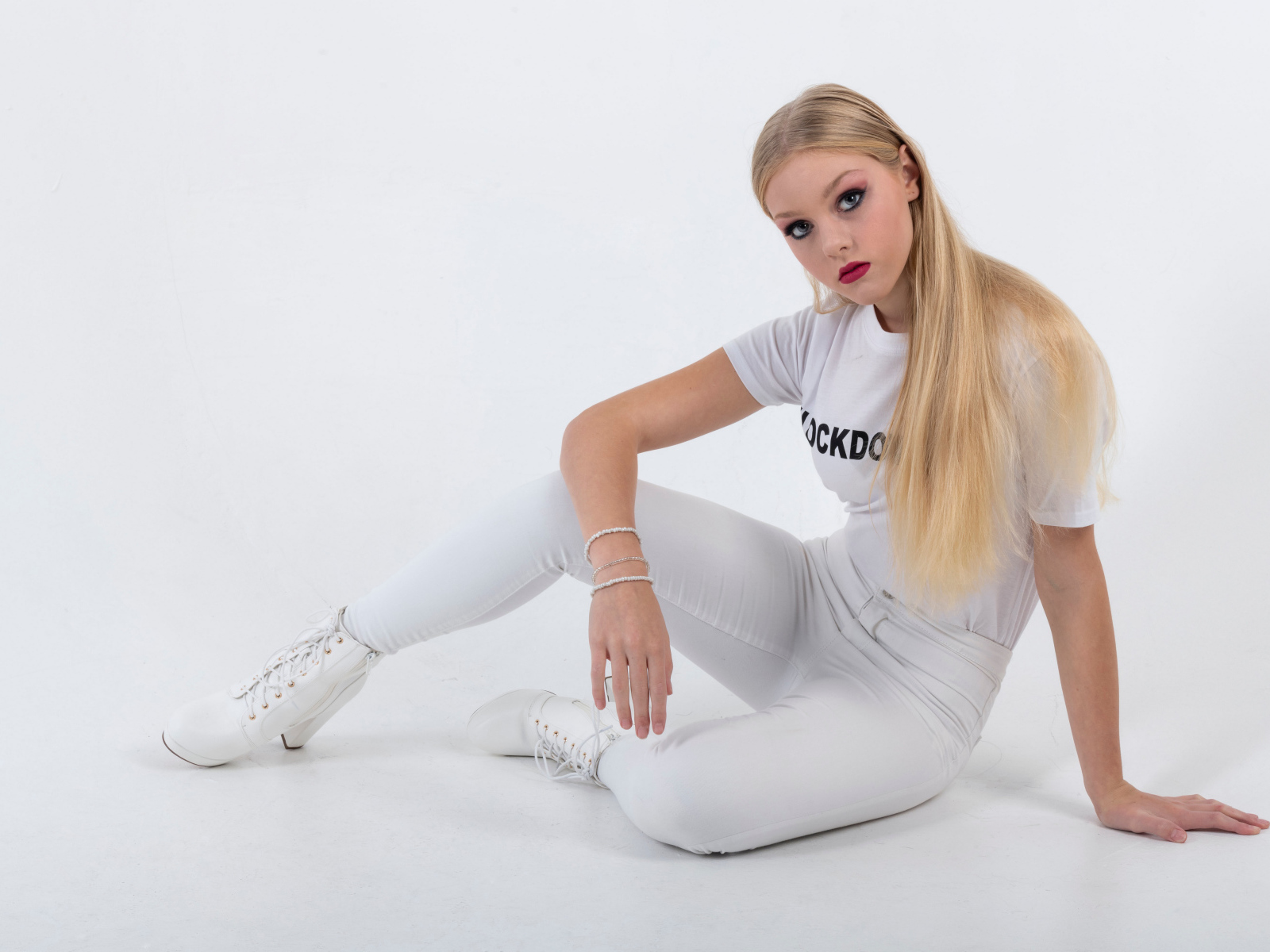 Красивая блондинка в белом костюме на сером фоне