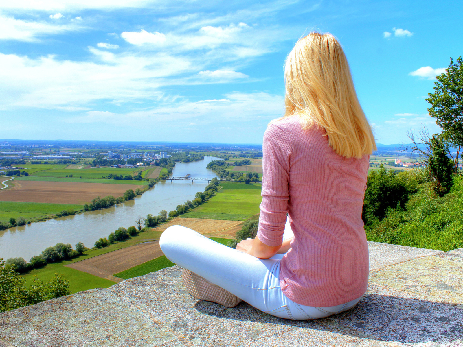 Красивая блондинка сидит на камне у реки