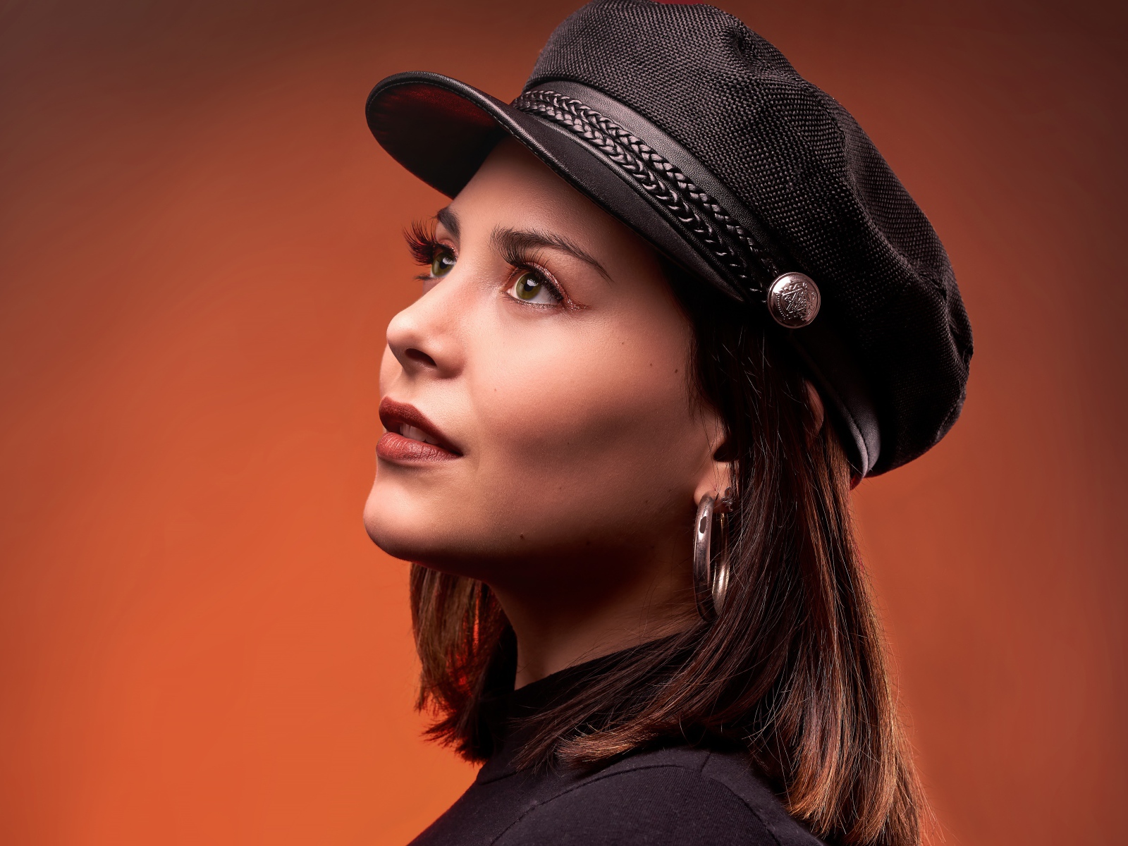 Красивая девушка в кепке на коричневом фоне