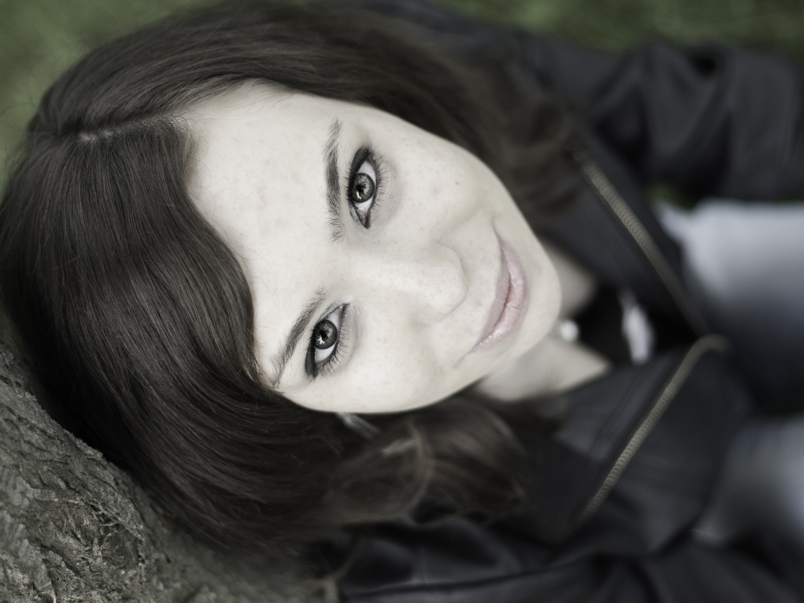 Красивая девушка смотрит вверх сидя под деревом  