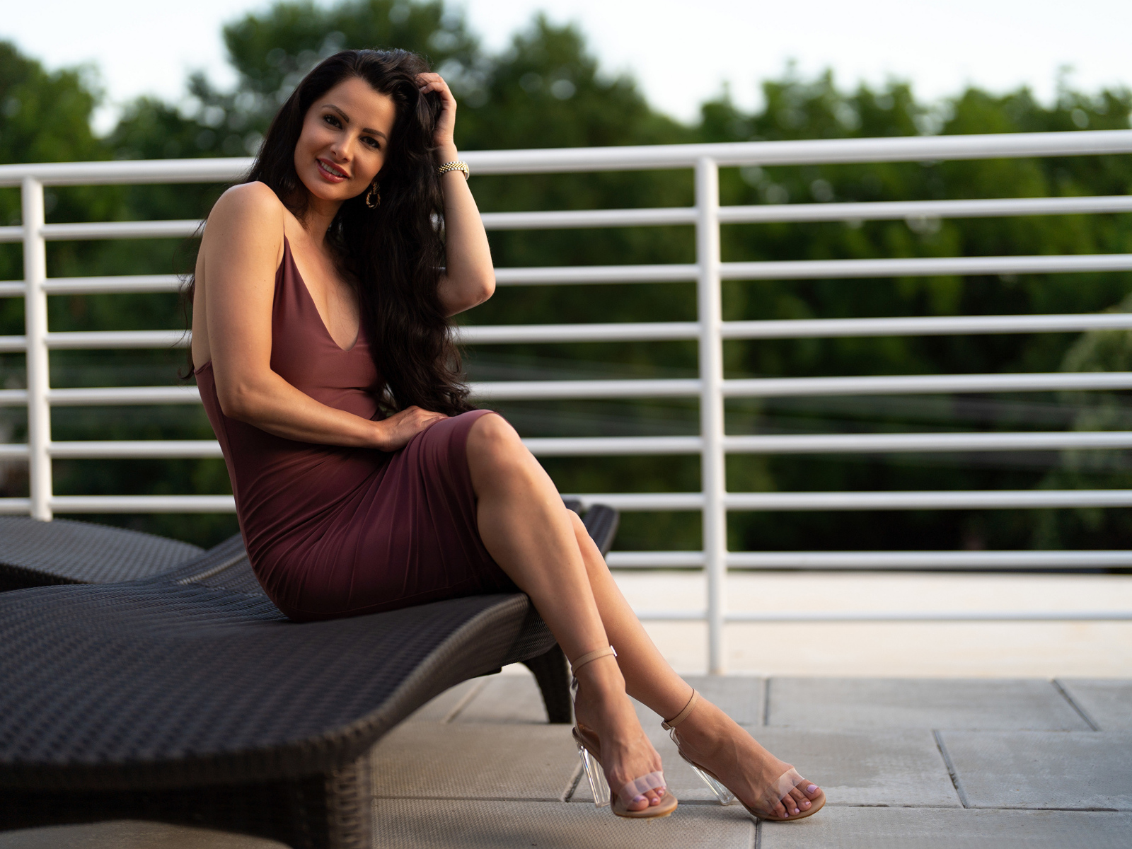 Красивая стильная брюнетка в платье сидит на диване