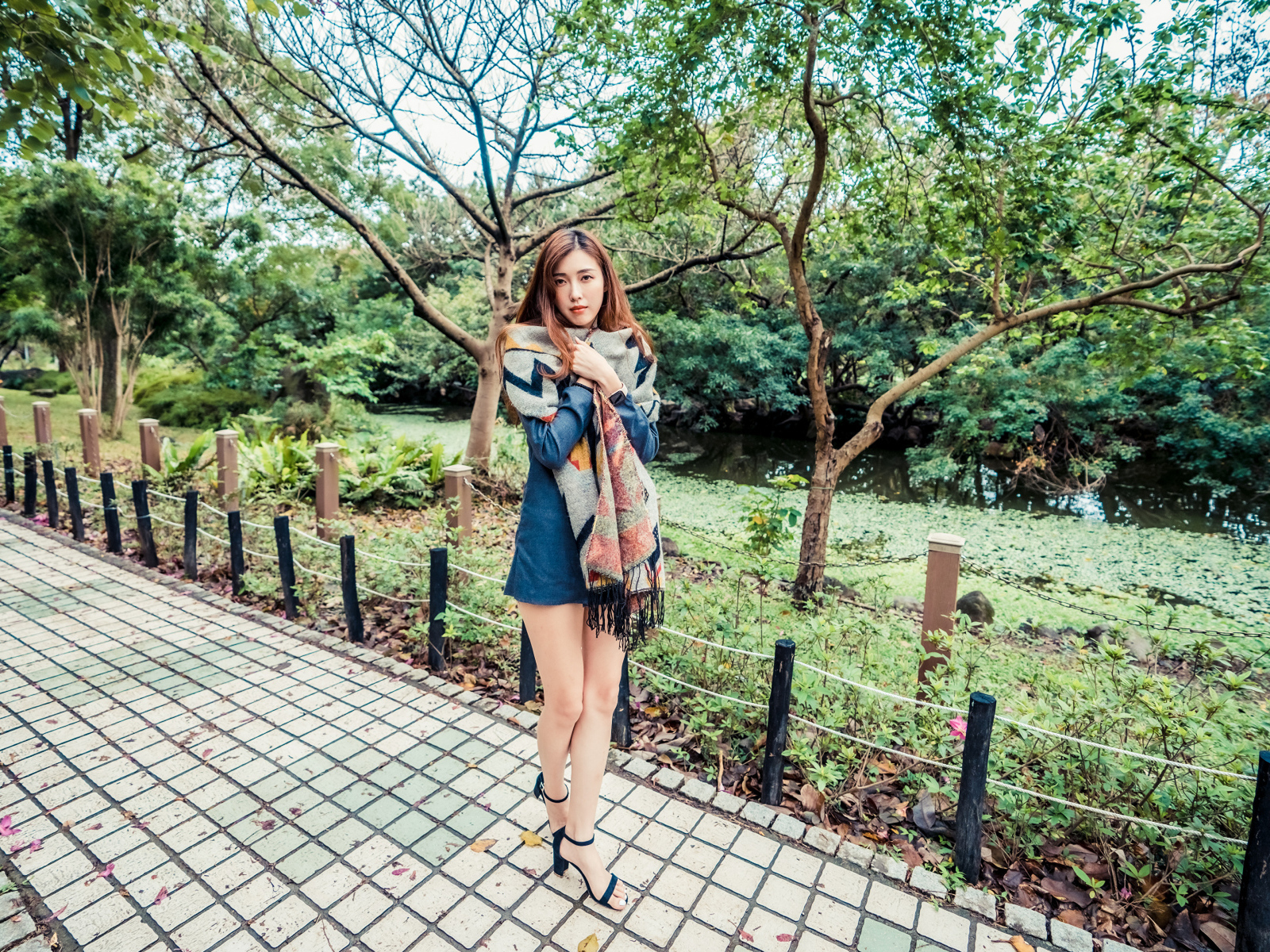 Милая девушка азиатка стоит в осеннем парке 