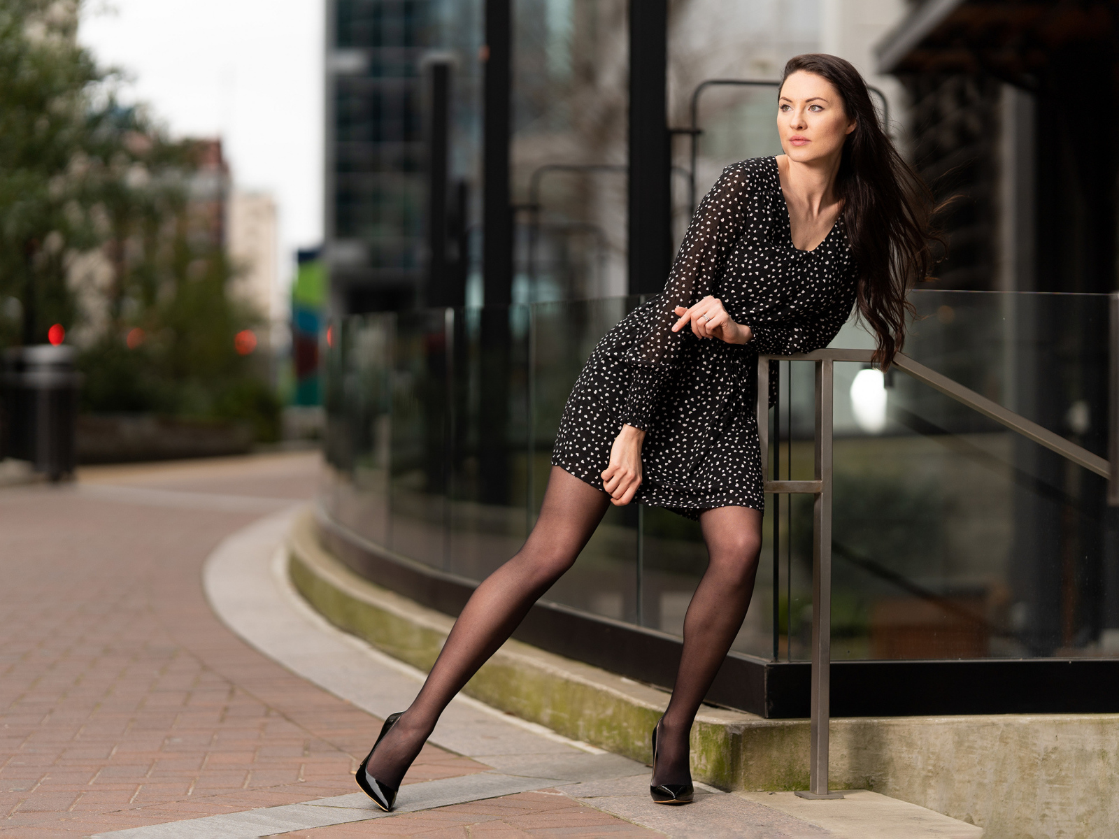 Девушка в черном платье в горошек у здания