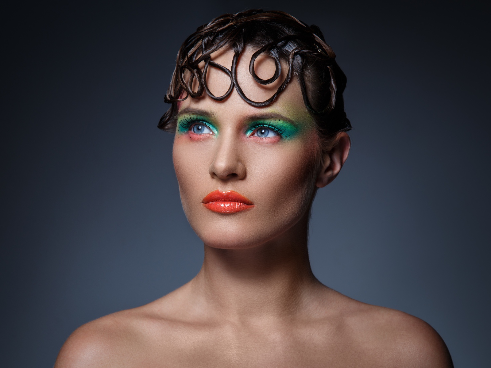 Девушка с ярким макияжем на сером фоне 