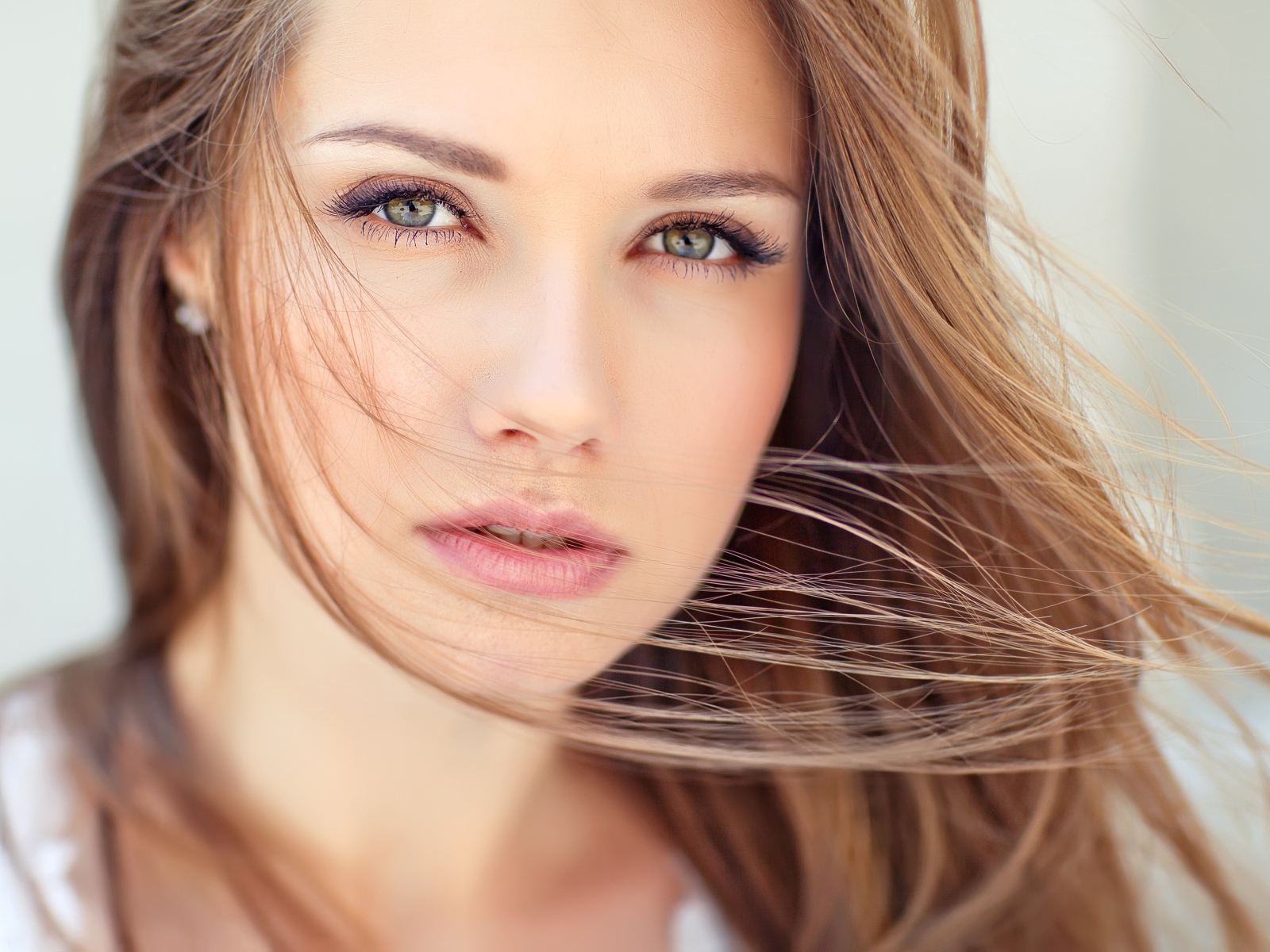 Волосы развеваются ветром на лице у девушки