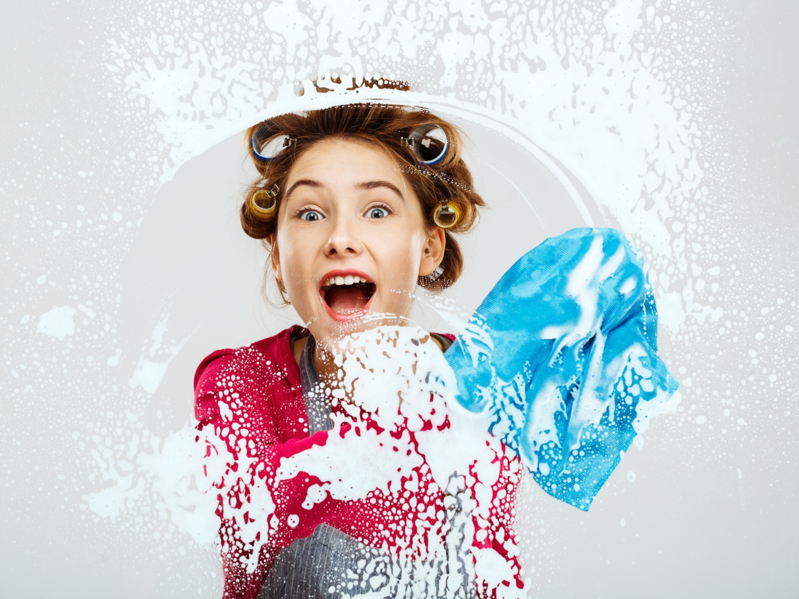 Молодая девушка в бигудях моет окно