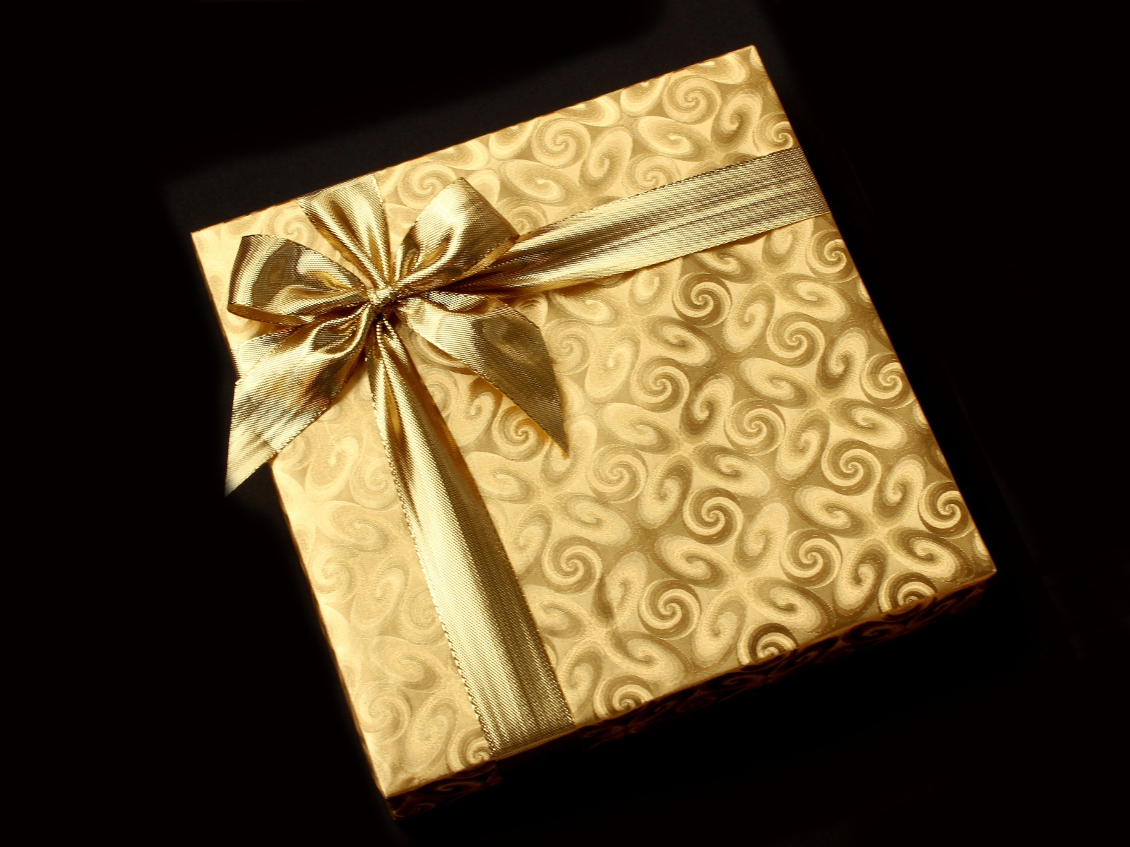 Золотая упаковка с подарком на черном фоне