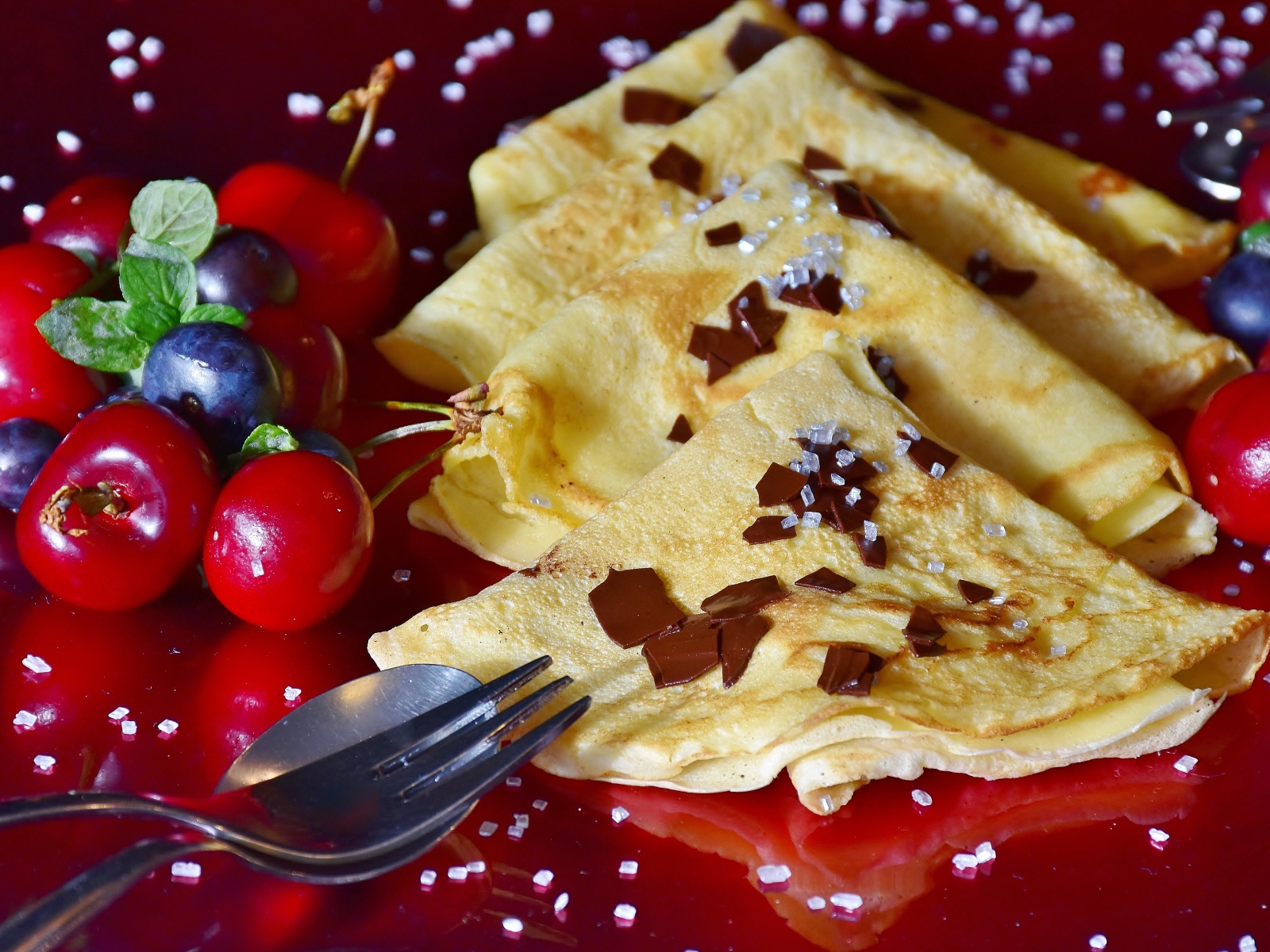 Тонкие блинчики с вишней и черникой на красном фоне масленице