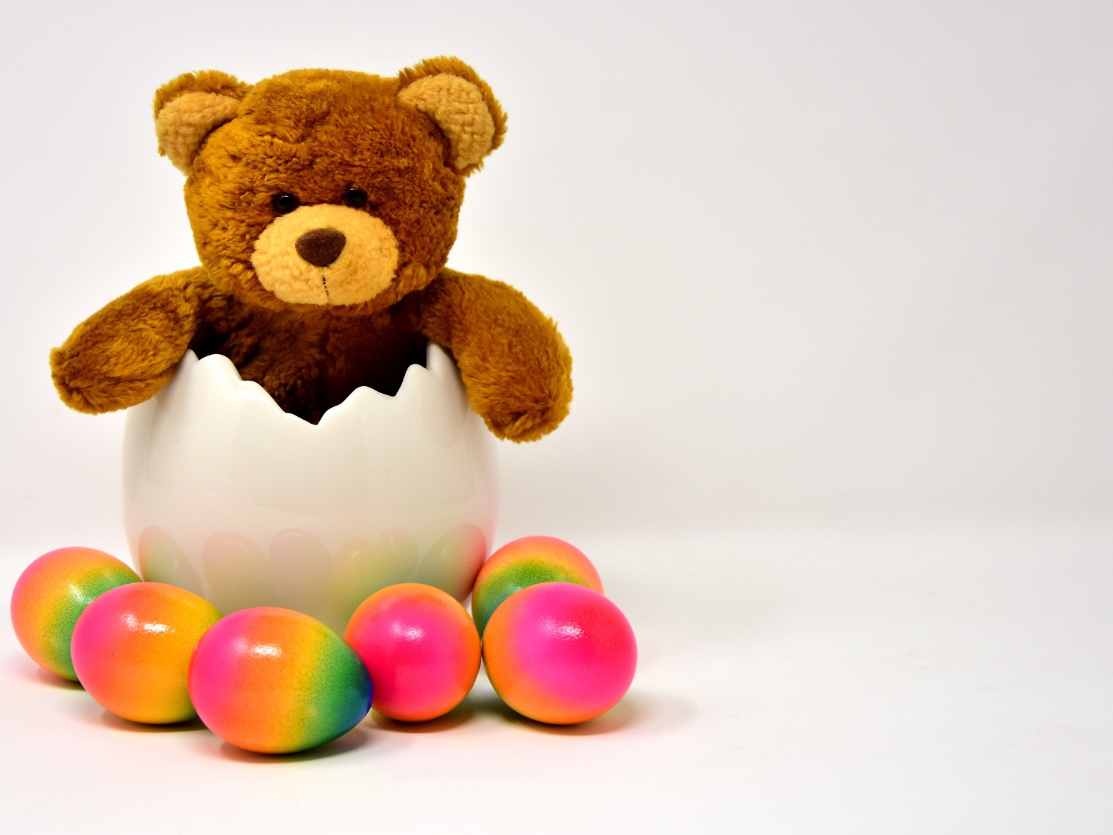 Медвежонок с яркими пасхальными яйцами на сером фоне