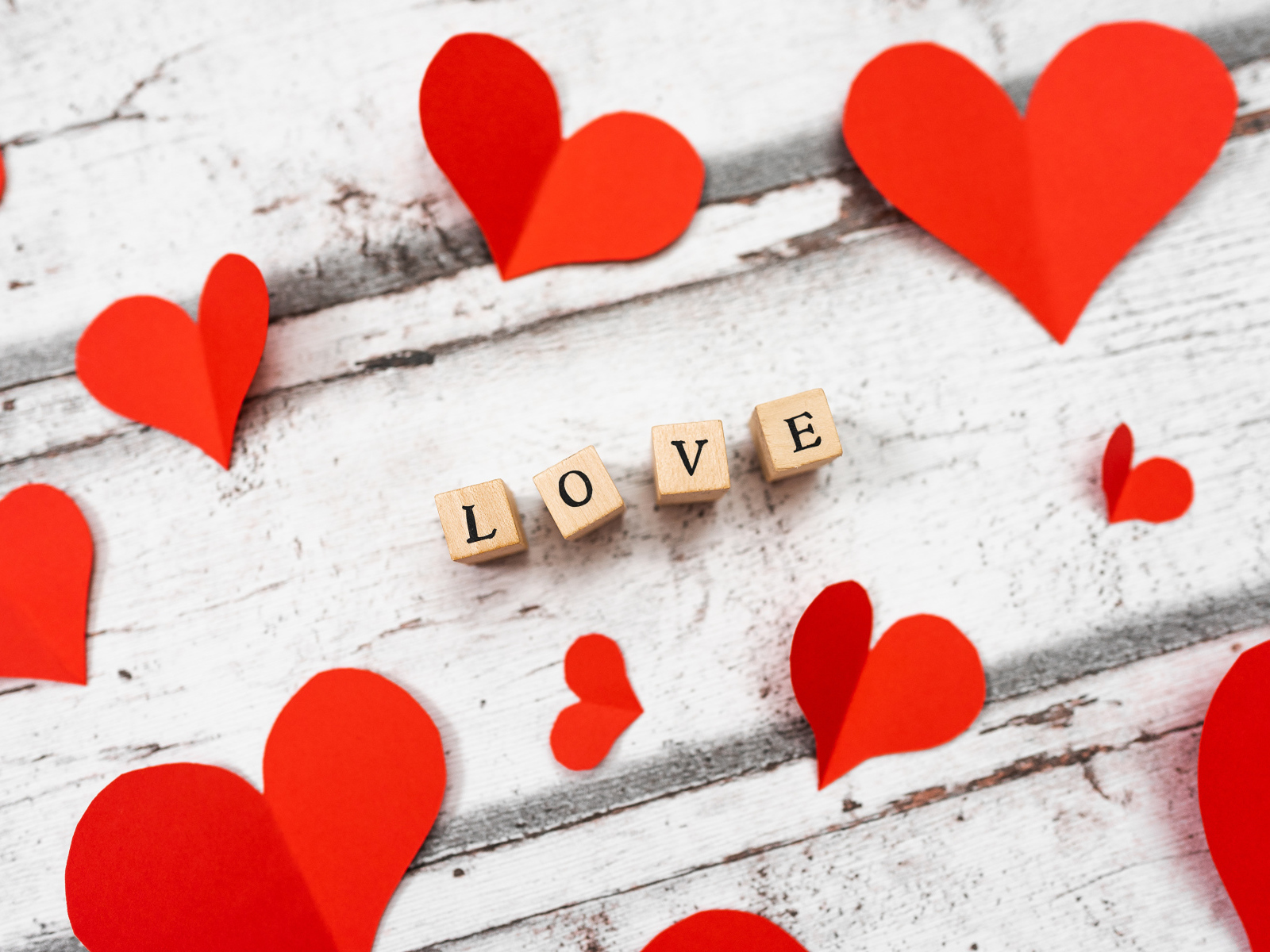 Красные сердечки и надпись любовь на деревянном столе 