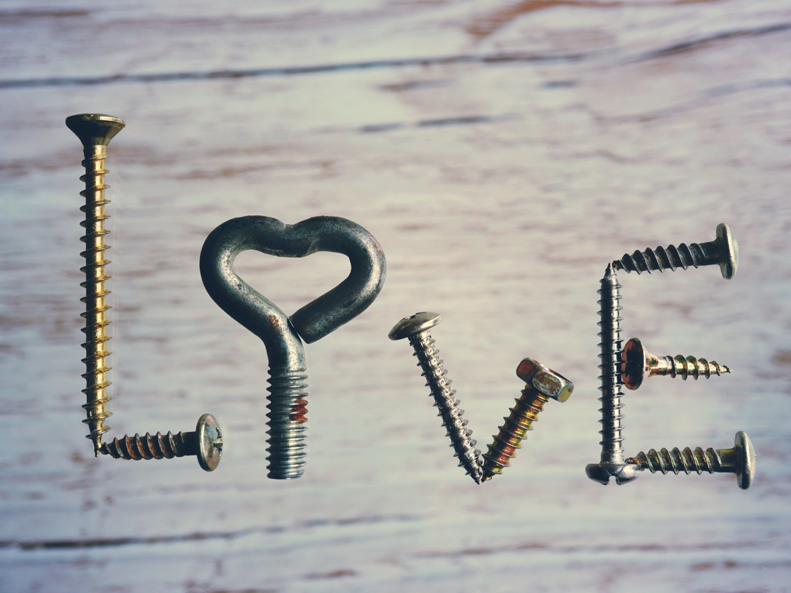 The inscription love made of self-tapping screws on a wood background