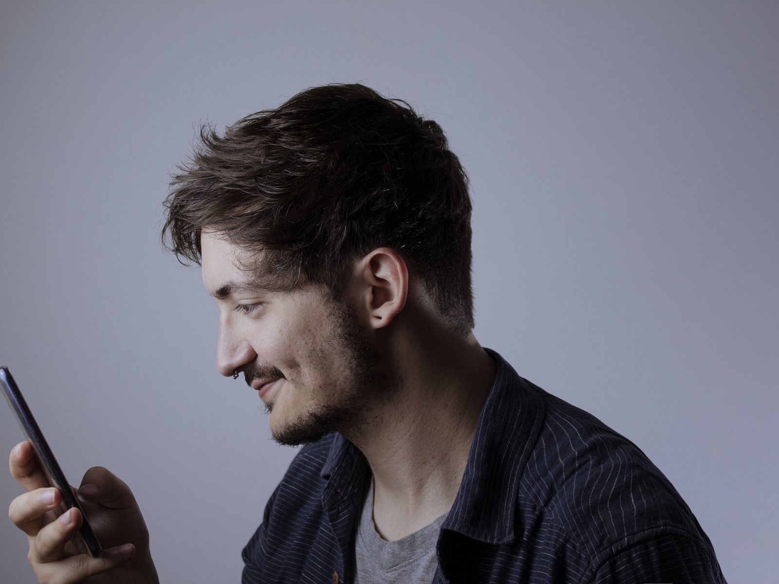 Мужчина с телефоном в руке на сером фоне 