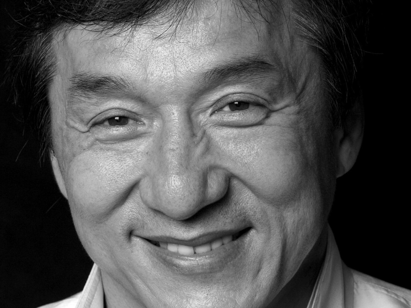 Лицо актера Джеки Чана на черном фоне