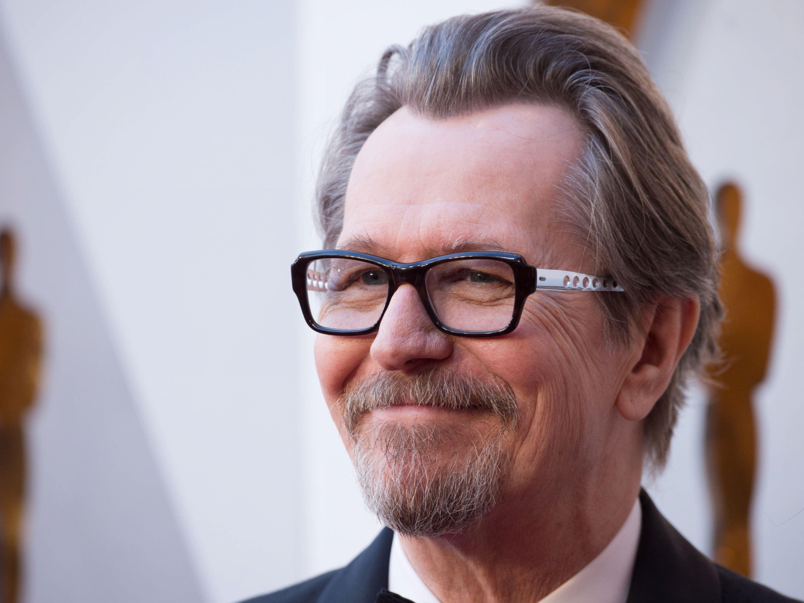 Улыбающийся мужчина, актер Гари Олдман в очках