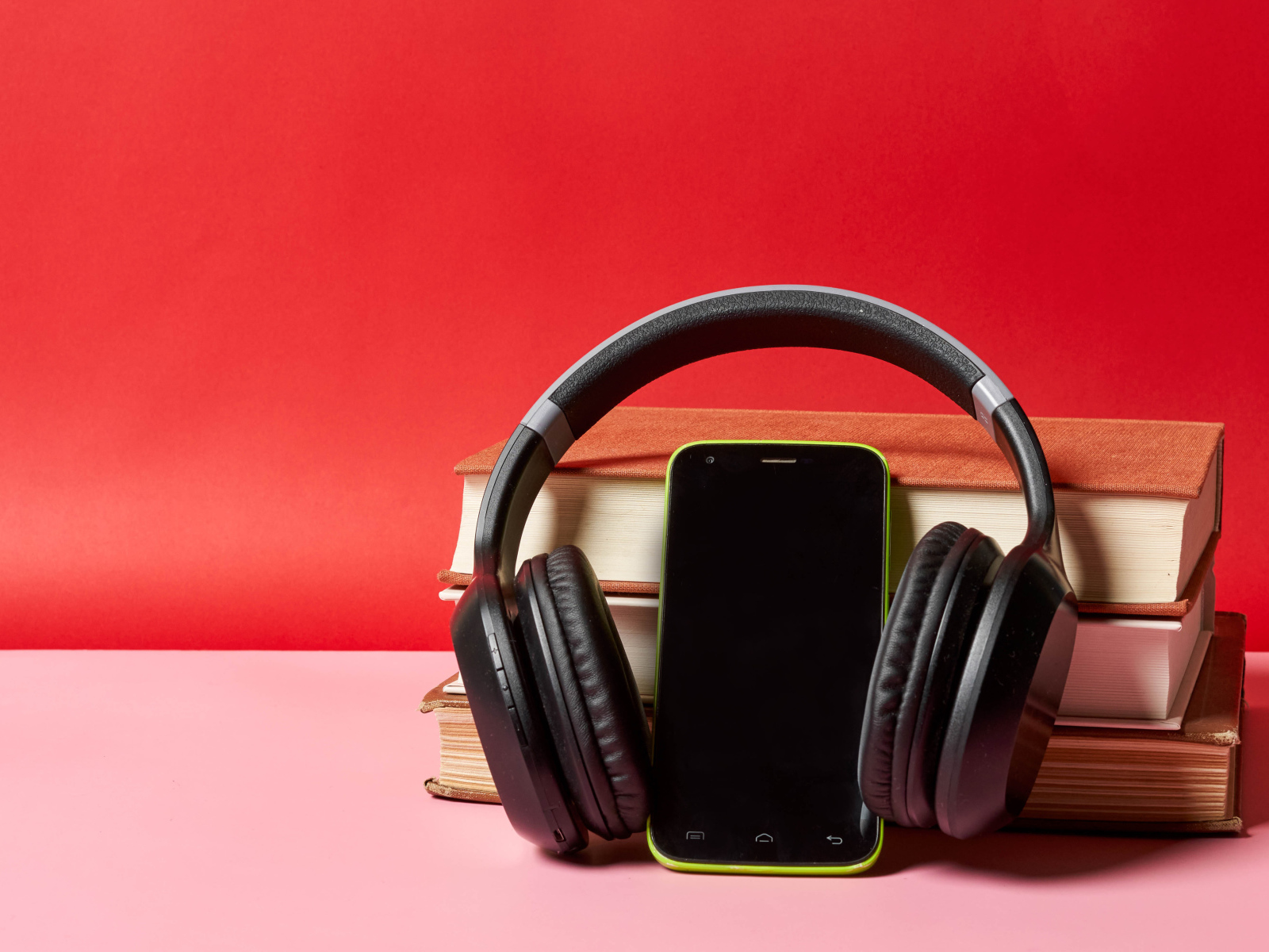 Смартфон, наушники и книги на красном фоне