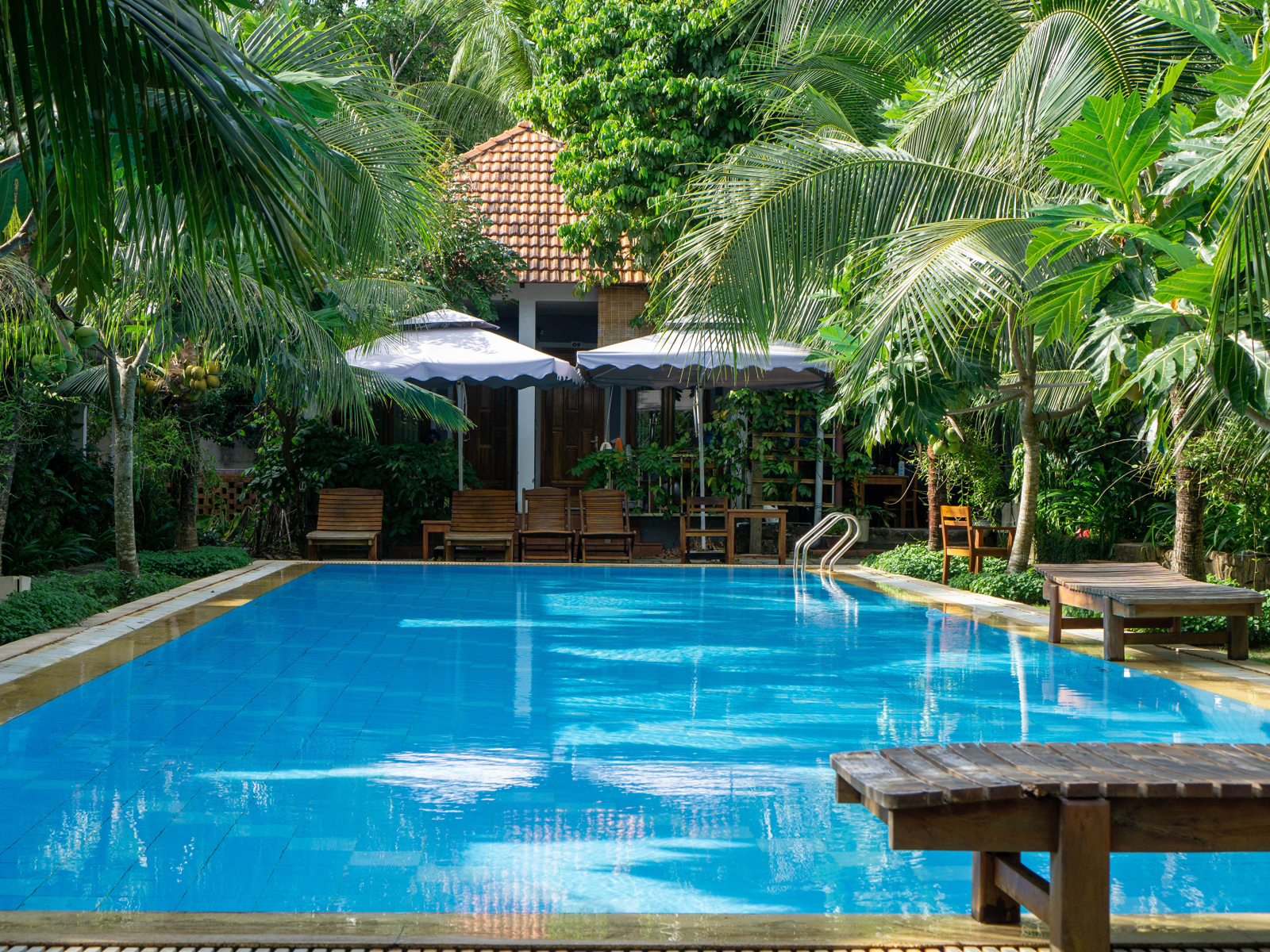 Бассейн с голубой водой у дома под пальмами