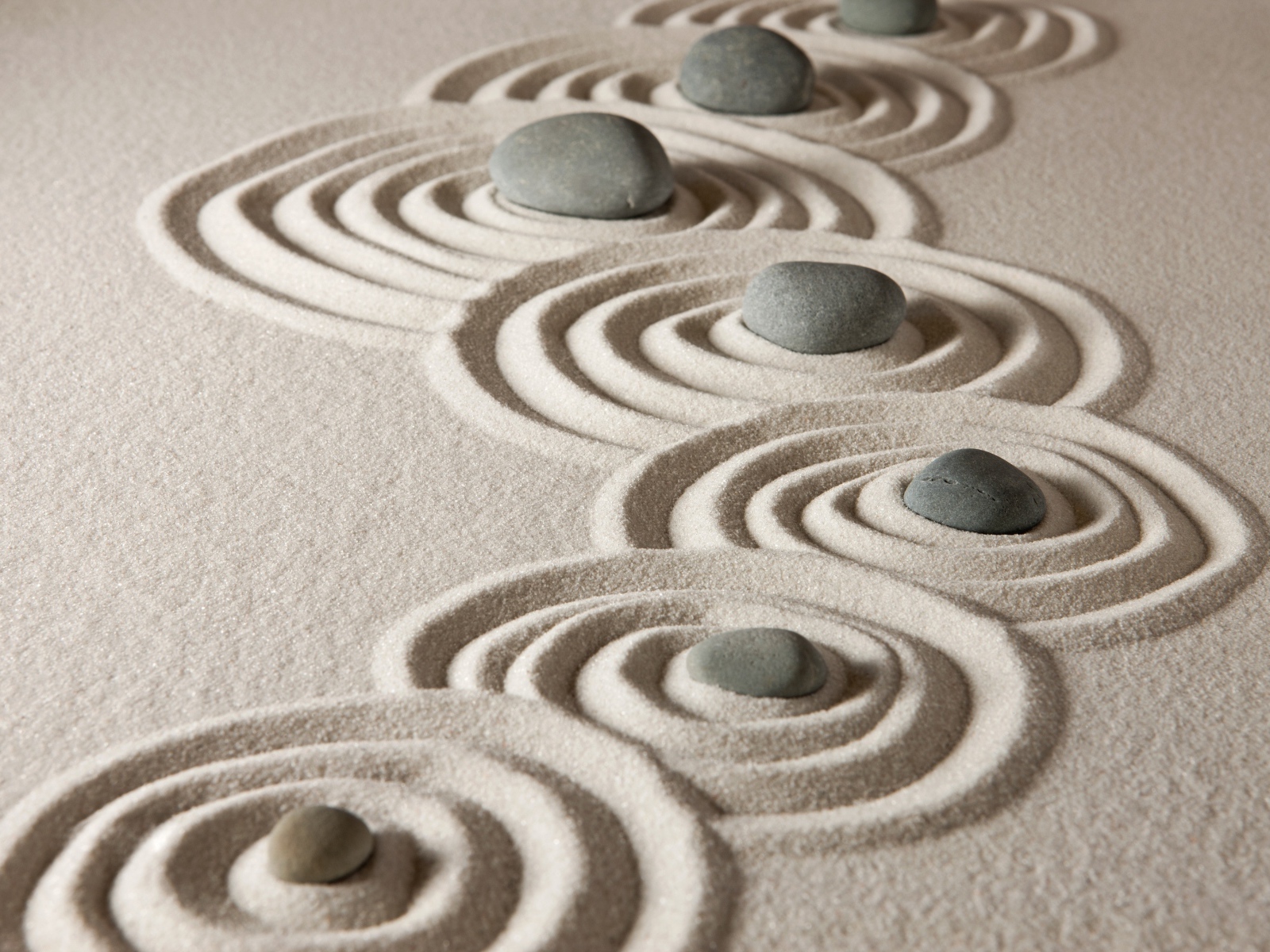 Маленькие серые камни с кругами на песке 