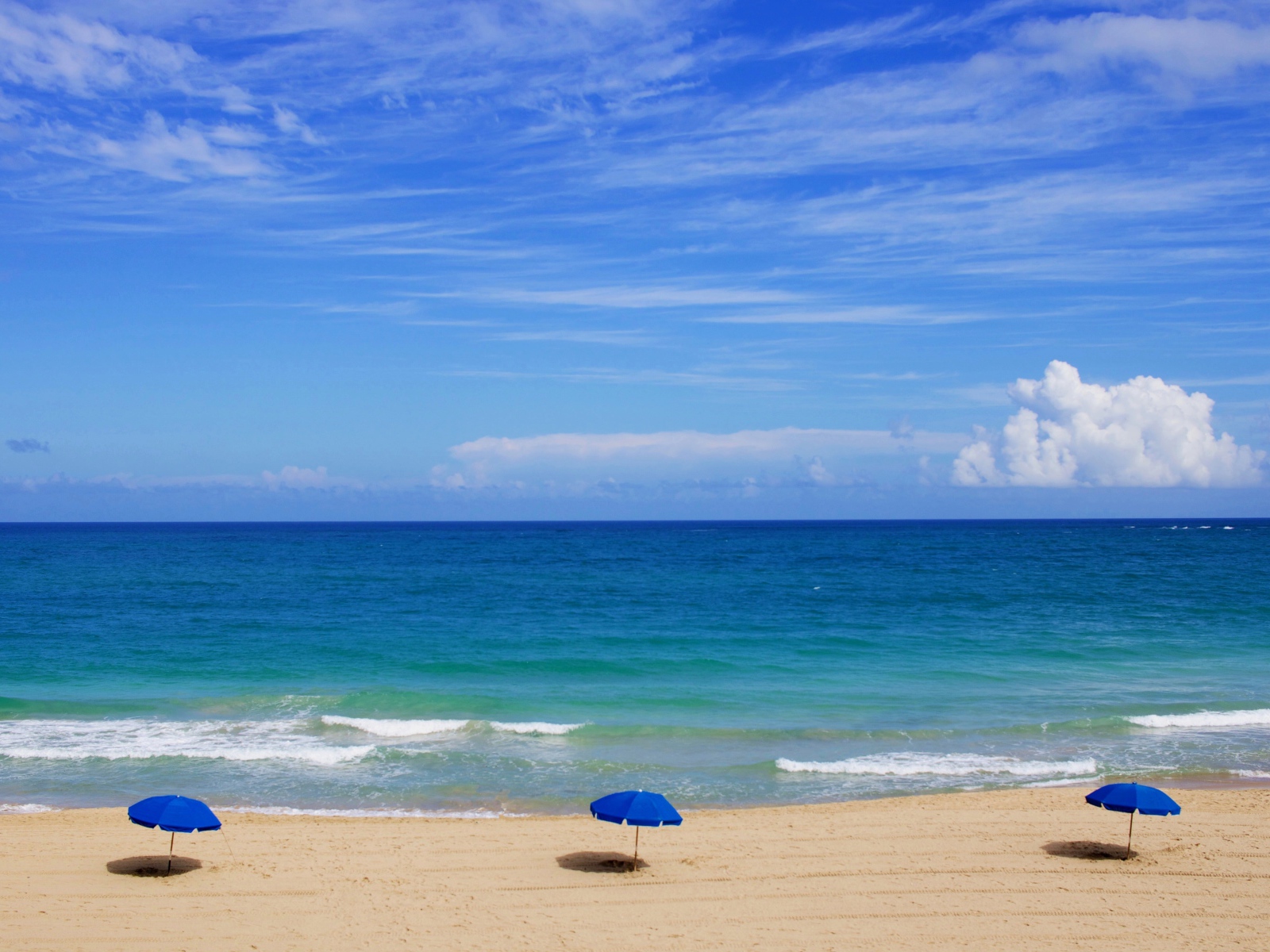 Зонтики на пляже у океана под голубым небом летом