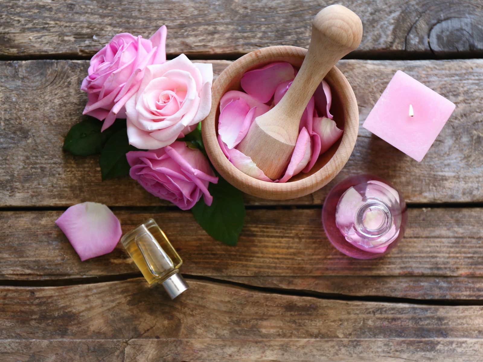 Лепестки розовой розы в ступке на столе с маслом