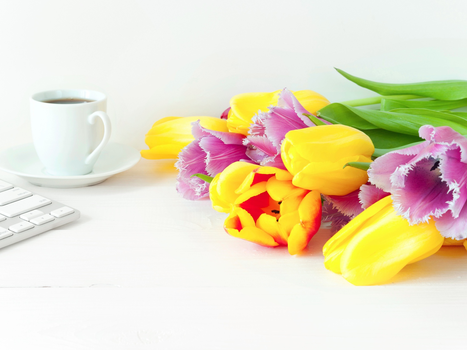 Желтые и розовые тюльпаны на столе с кофе