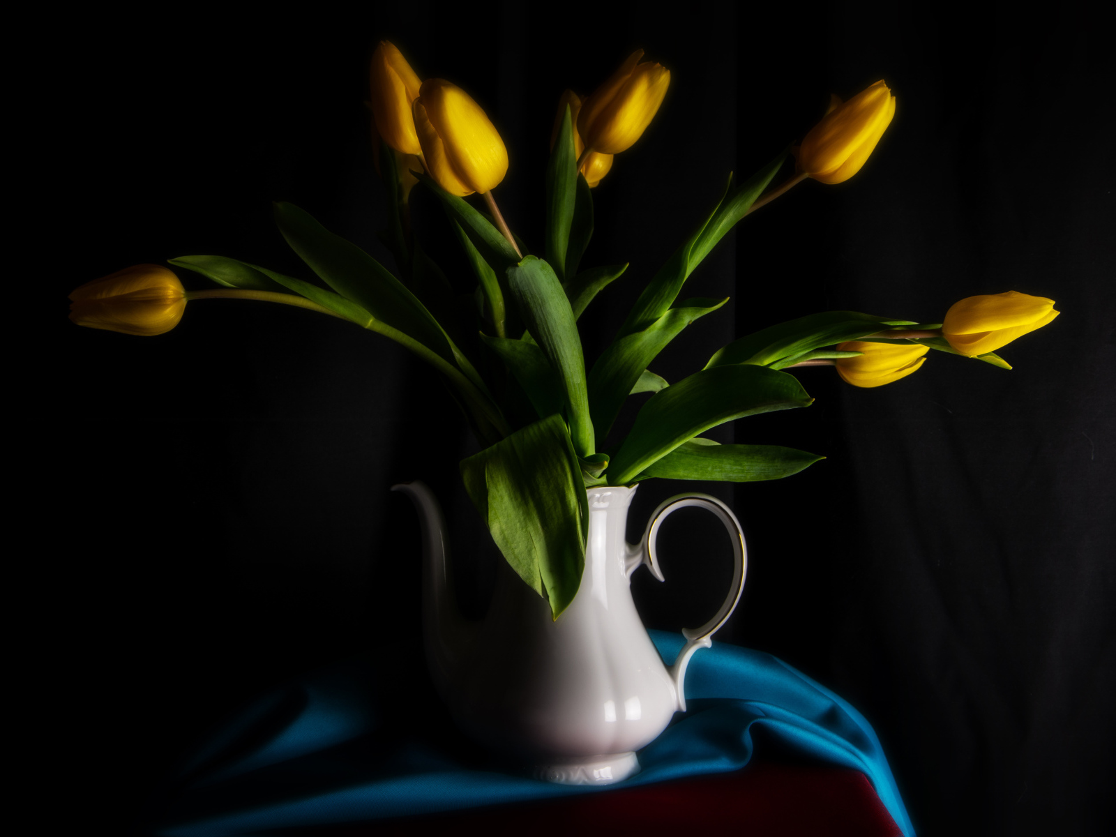 Желтые тюльпаны в белой вазе на черном фоне