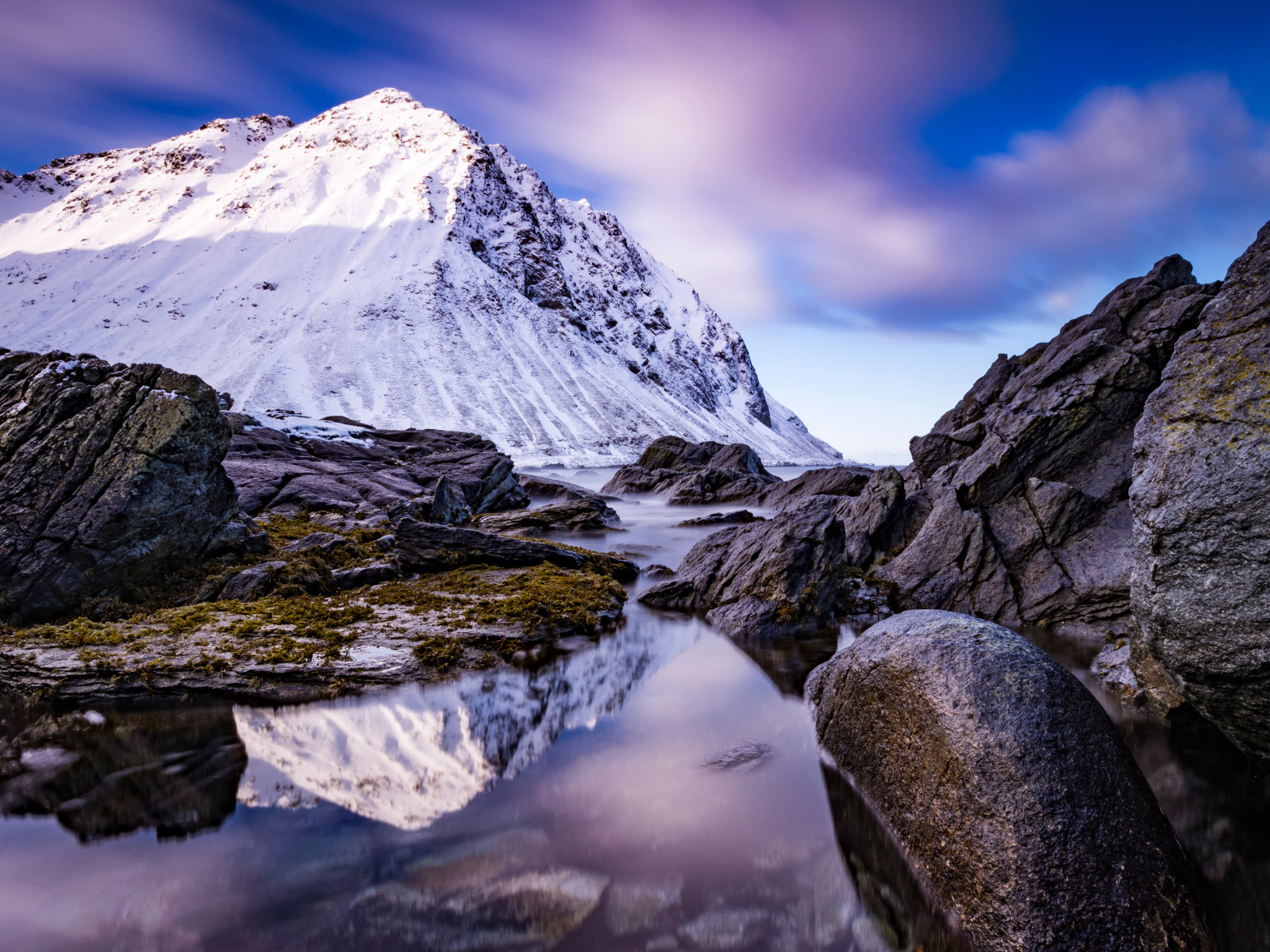 Заснеженные горы у ручья под красивым небом 