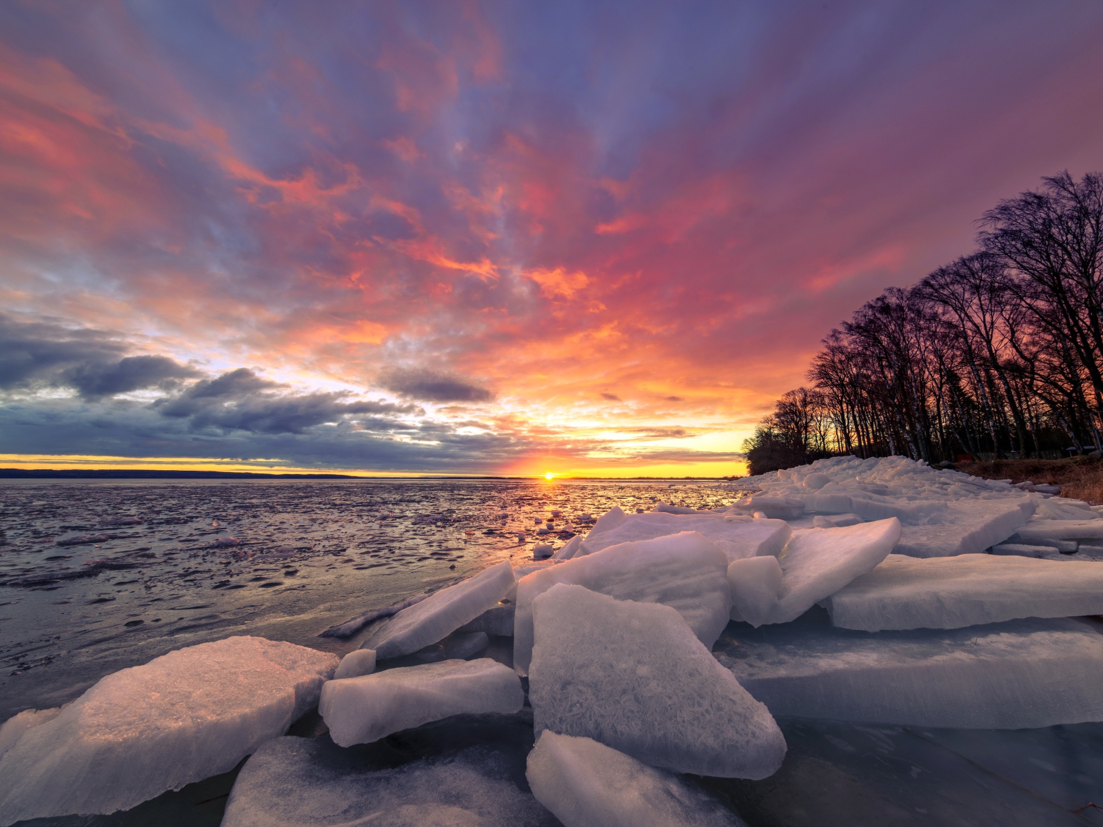 Глыбы льда лежат на берегу моря на закате