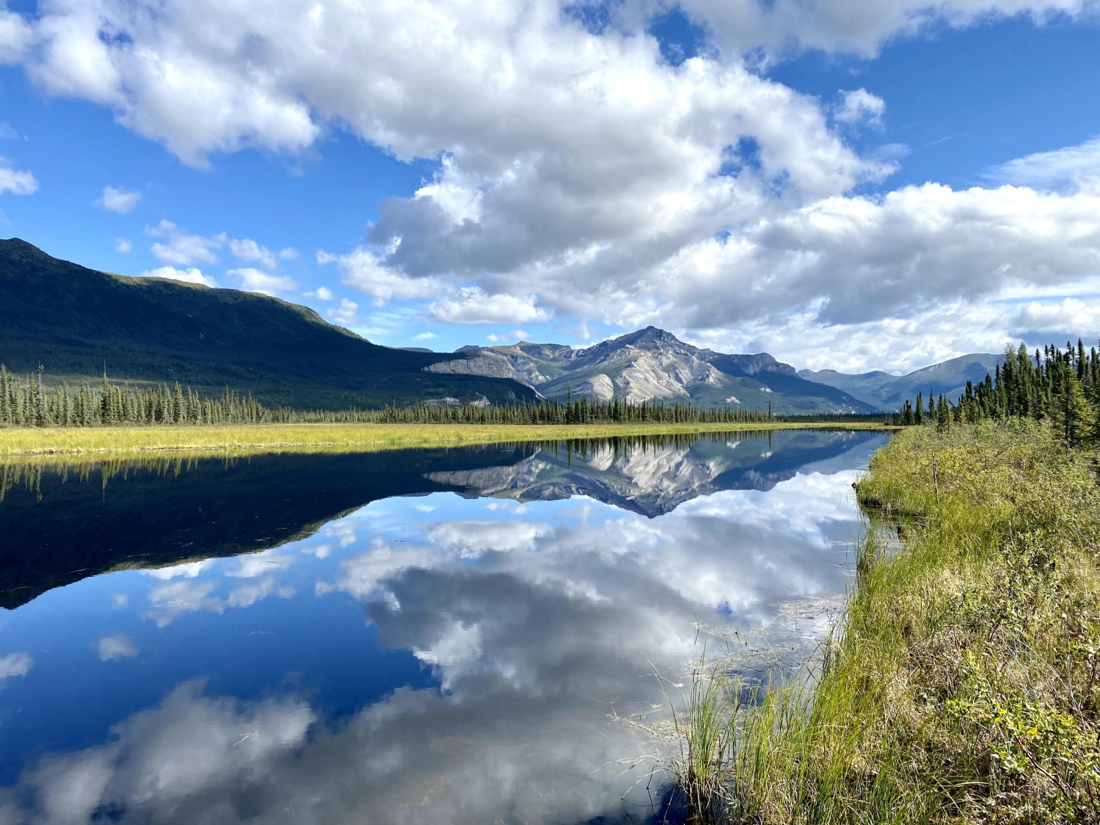 Небо с белыми облаками отражается в реке 