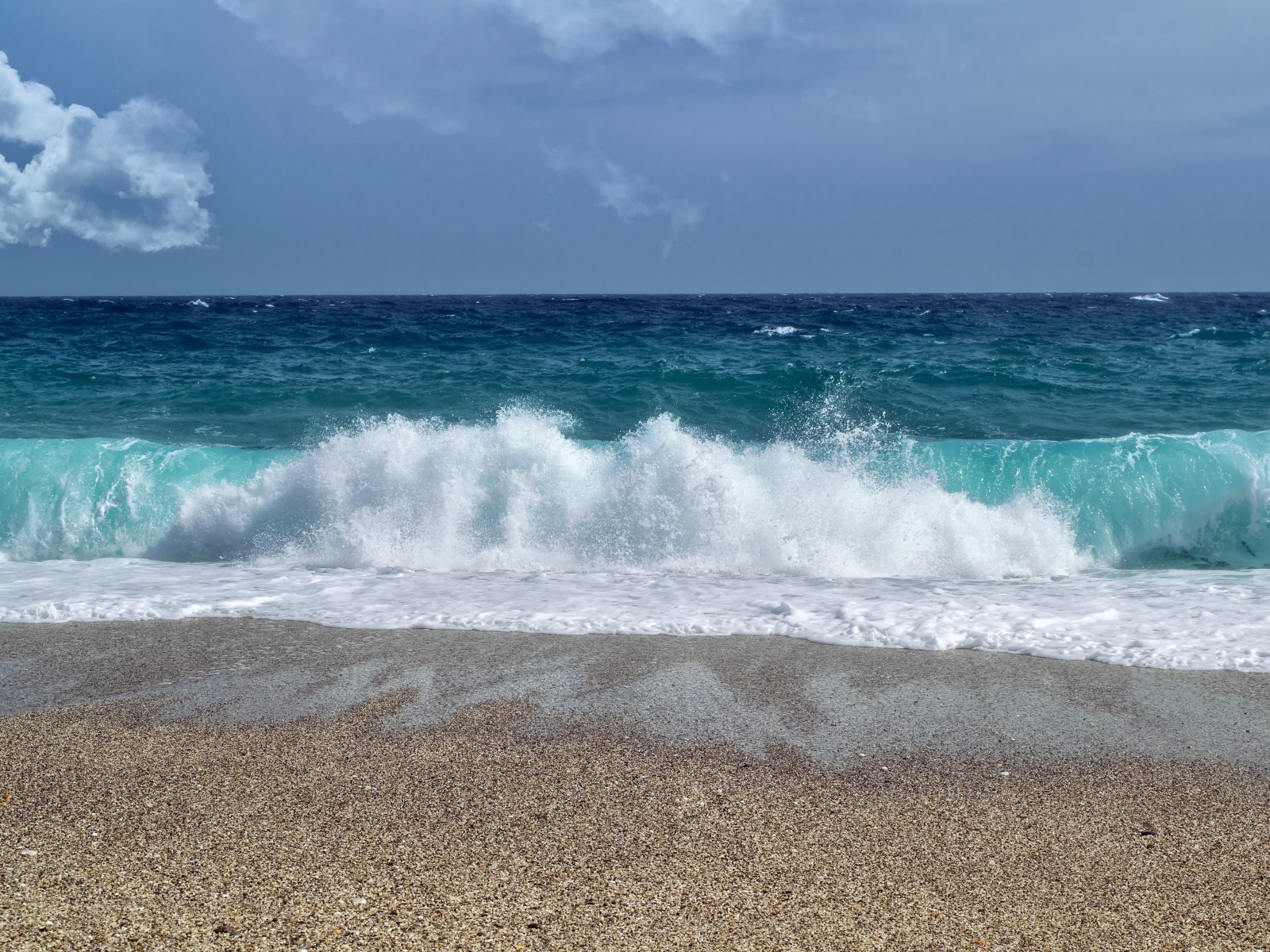 Голубые волны океана на мокром песке 